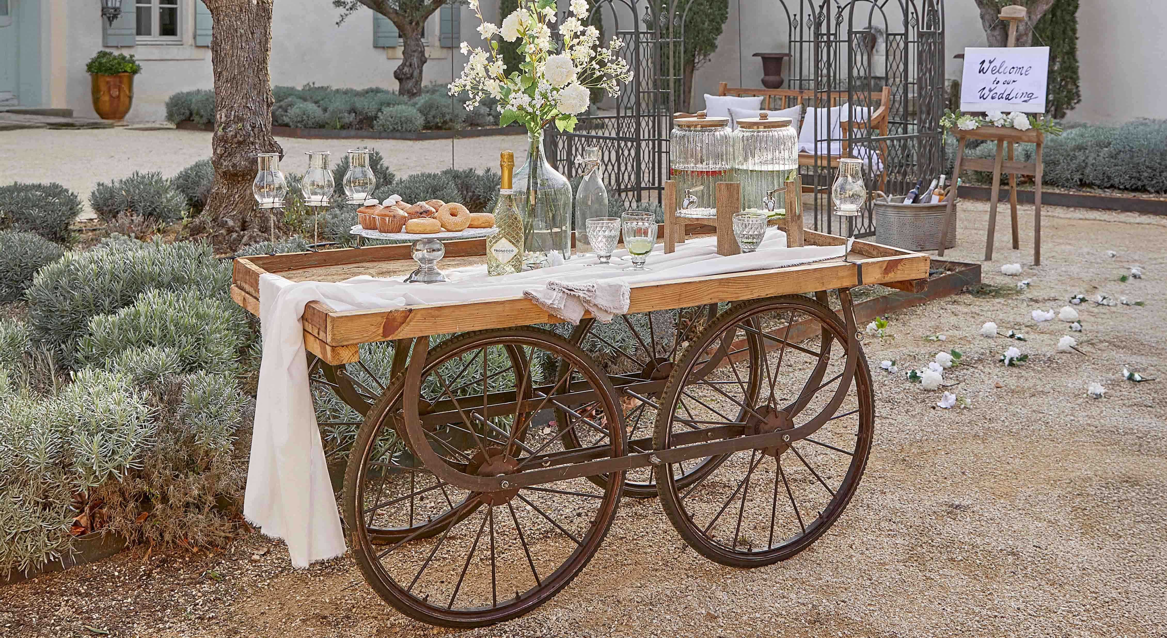 Holzwagen mit Metallrädern, dekoriert für Hochzeit mit Blumen und Getränken