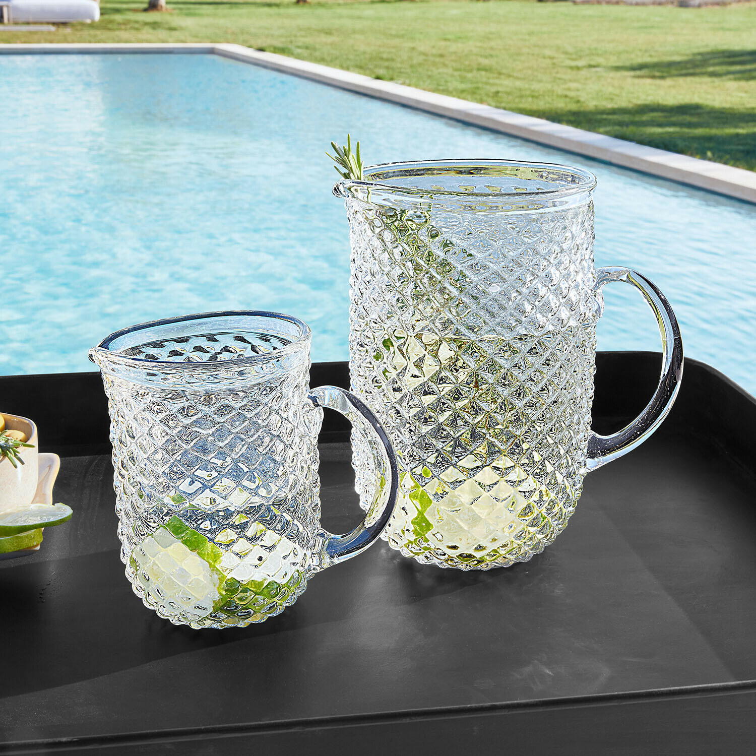 Krug 2er Set Ivorias Glaskrug und Becher mit Diamantmuster, transparent mit Limettenscheiben, auf schwarzem Tablett am Pool