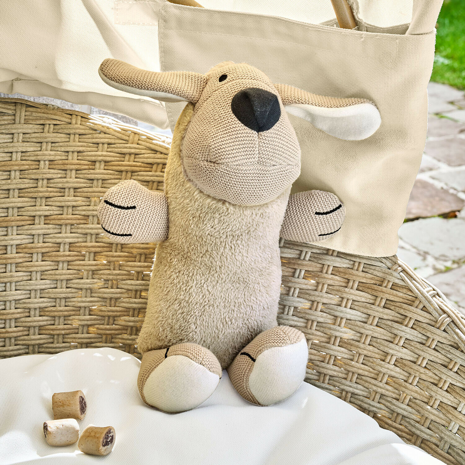 Hundespielzeug Wuffie Beige Kuscheltier Schaf mit weichem Plüsch und gestrickten Details auf Rattanstuhl