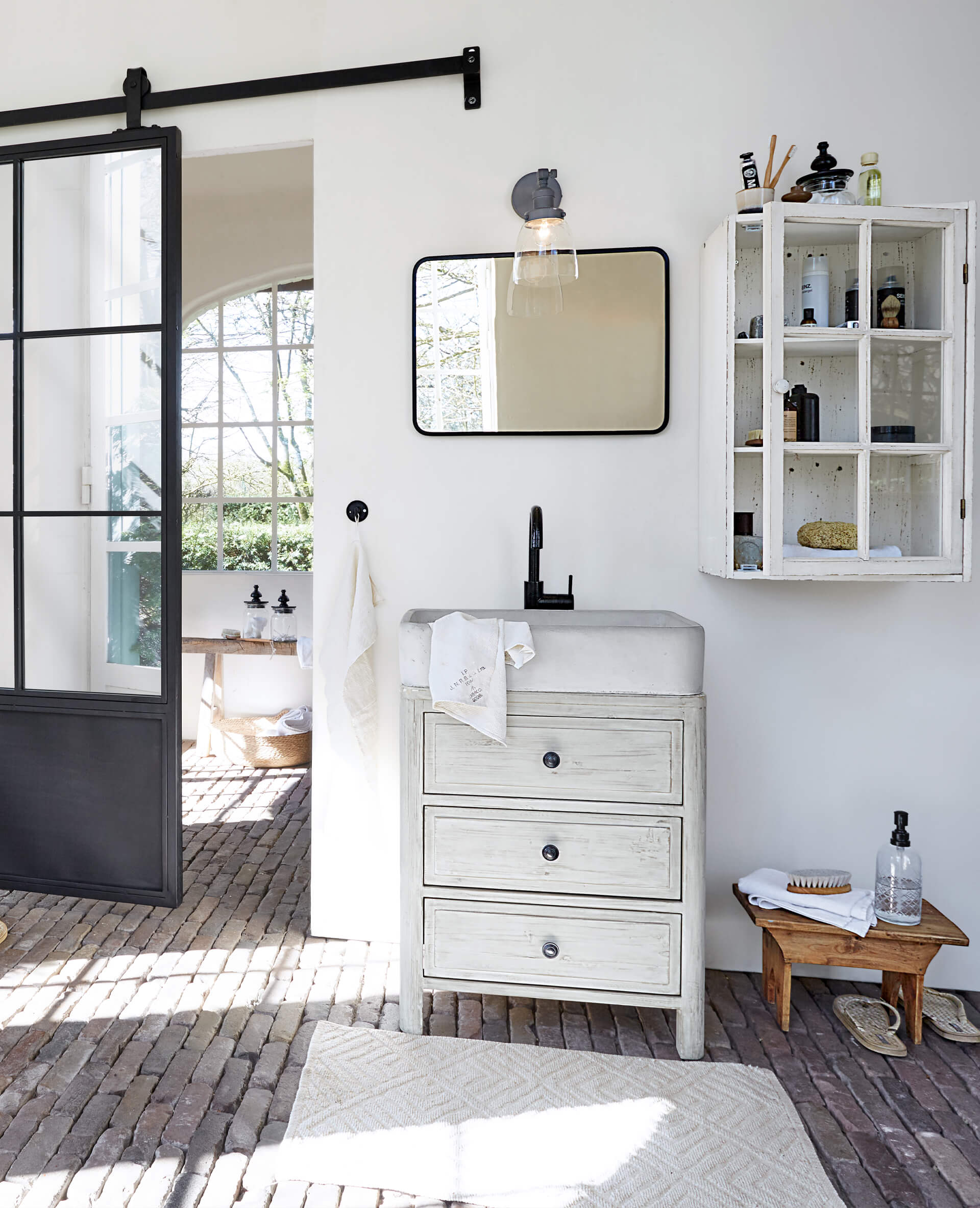 Badezimmer mit weissem Holzschrank, Betonwaschbecken und schwarzem Wasserhahn, rechteckigem Spiegel und Wandregal