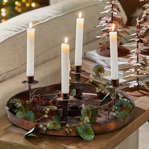 Metall-Adventskranz mit vier weissen Kerzen und Blattdekoration auf Holztisch im Wohnzimmer
