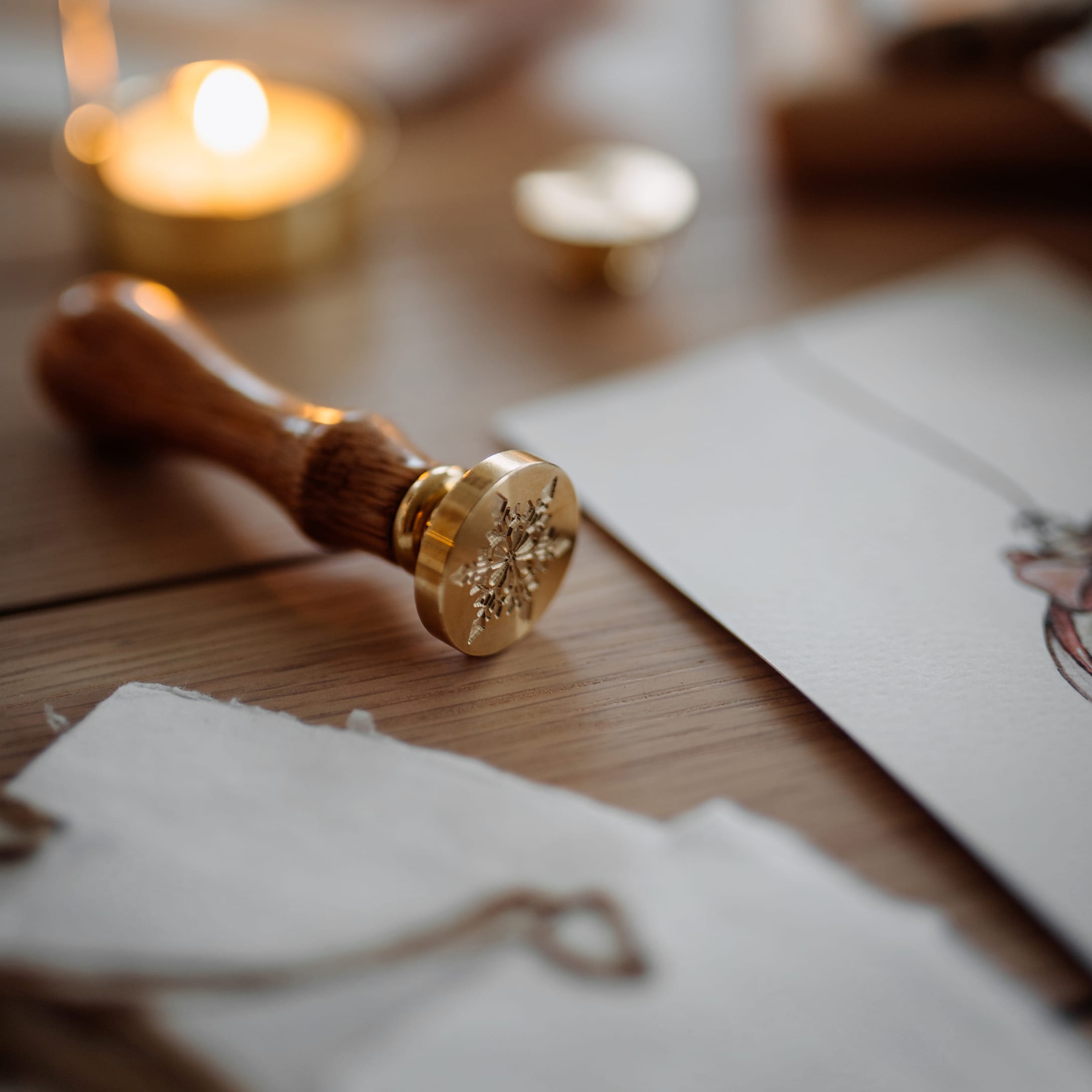 Messing- und Holzsiegelstempel mit Schneeflockenmotiv auf Holztisch zum Verpacken von Geschenken