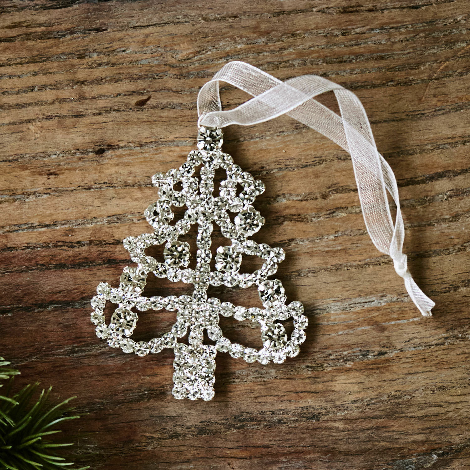 Anhänger Orilane Glänzender Christbaumschmuck in Baumform aus Kristallen mit weissem Band auf Holzuntergrund