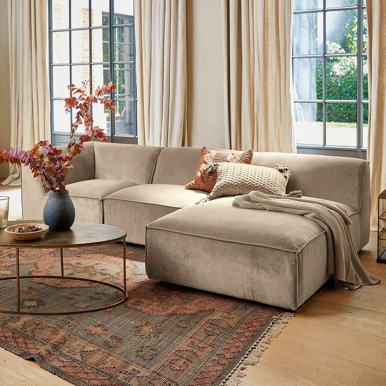 Sofa McLean Beige Eckcouch aus weichem Stoff im stilvollen Wohnzimmer mit Teppich und rundem Couchtisch