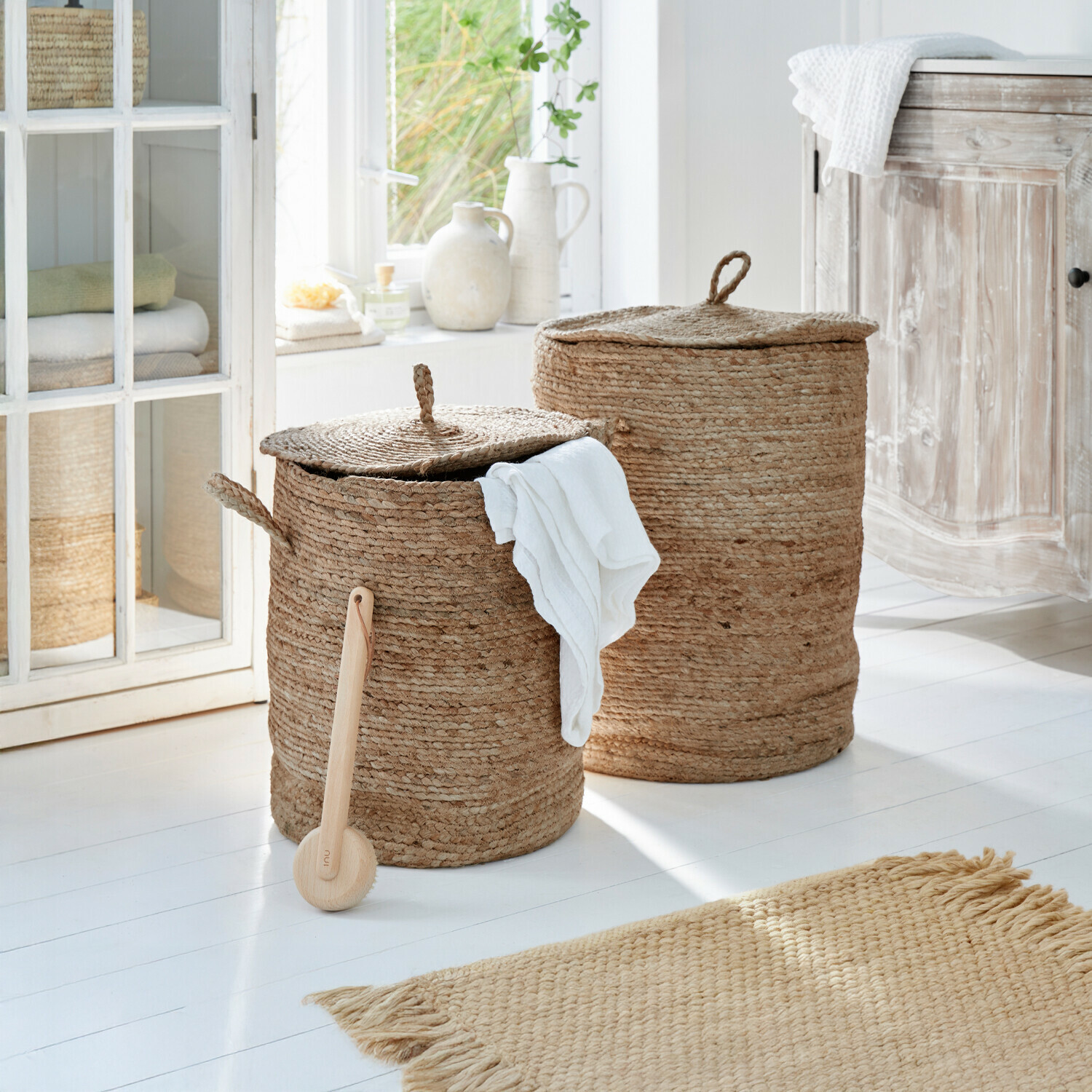 Wäschekorb 2er Set Kory Zwei runde Wäschekörbe aus natürlicher Jute in Beige in einem hellen Badezimmer