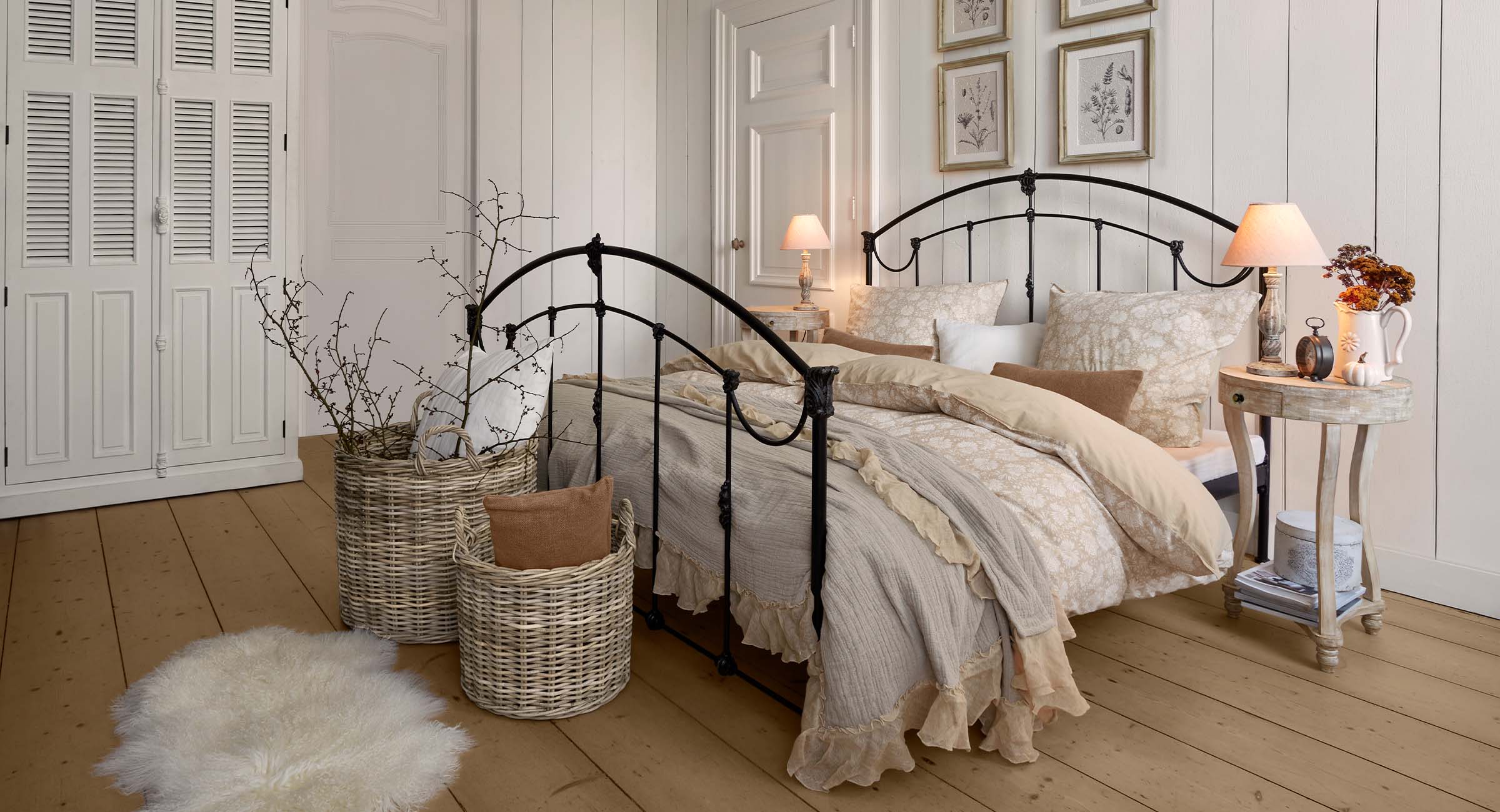 Gemütliches Schlafzimmer mit schwarzem Metallbett und cremefarbiger Bettwäsche mit Blumenmuster