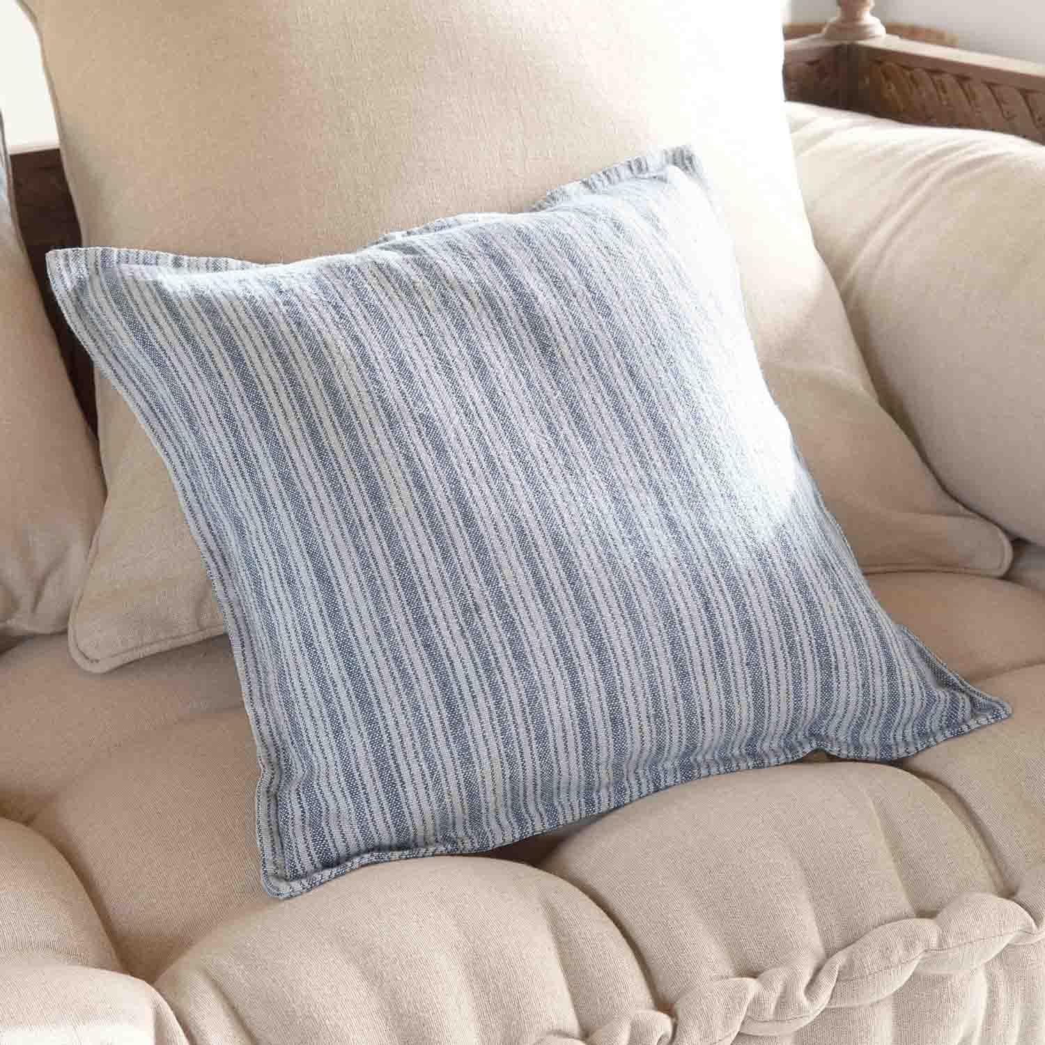 Dekoratives Kissen mit blau-weiß gestreiftem Bezug auf beigem Sofa, weicher Stoff, Wohnstil