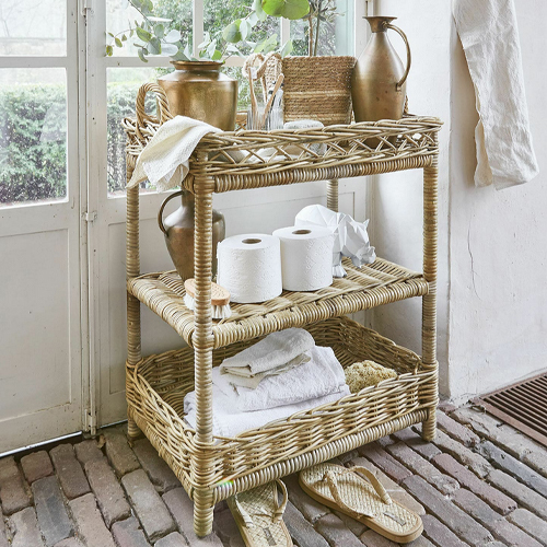 Dreistufiges Regal aus natürlichem Rattan mit Dekorationen und Handtüchern, stilvolles Badezimmermöbel.
