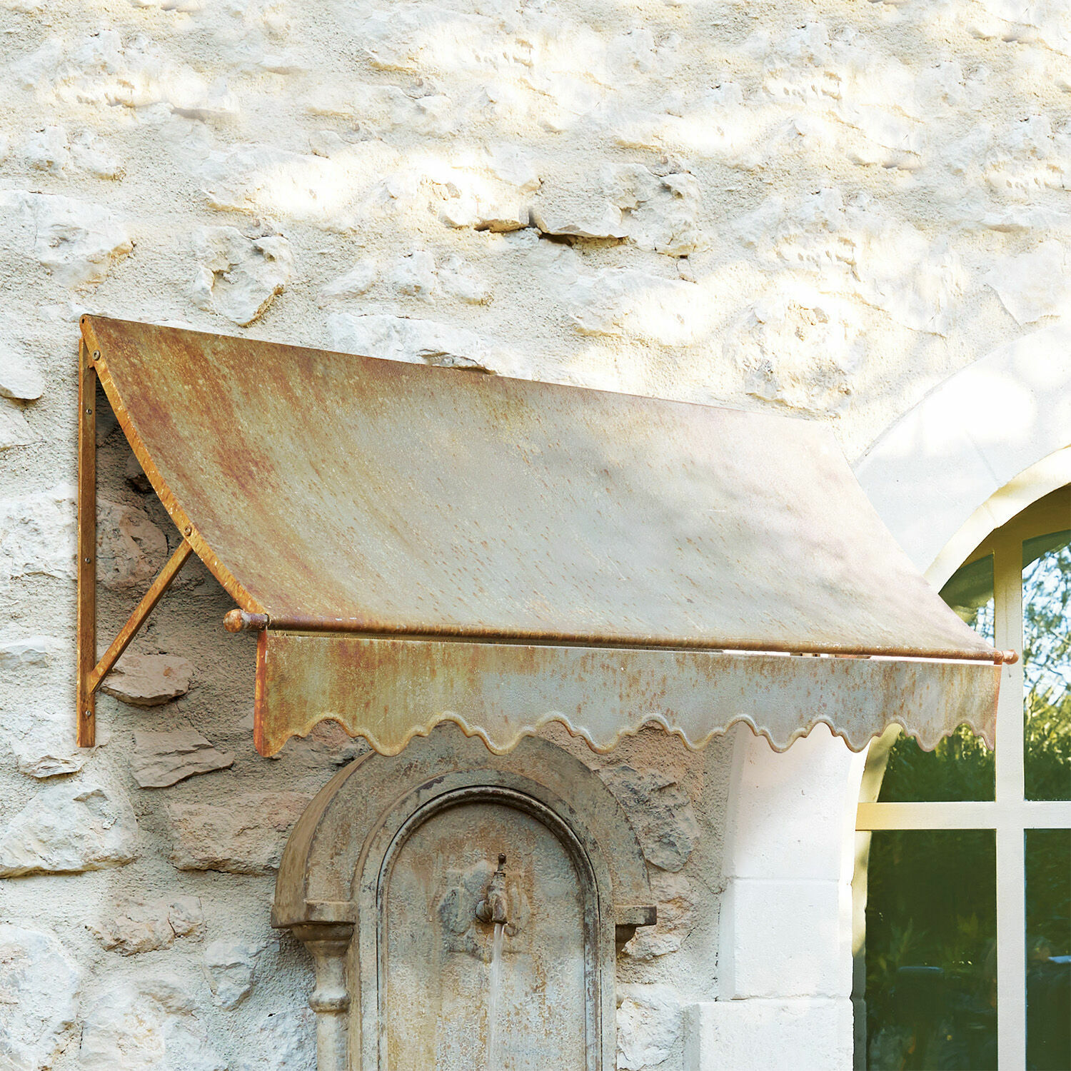 Vordach Maltot Verrostetes Metallvordach an einer Steinmauer mit Fenster und antiker Wasserfontäne