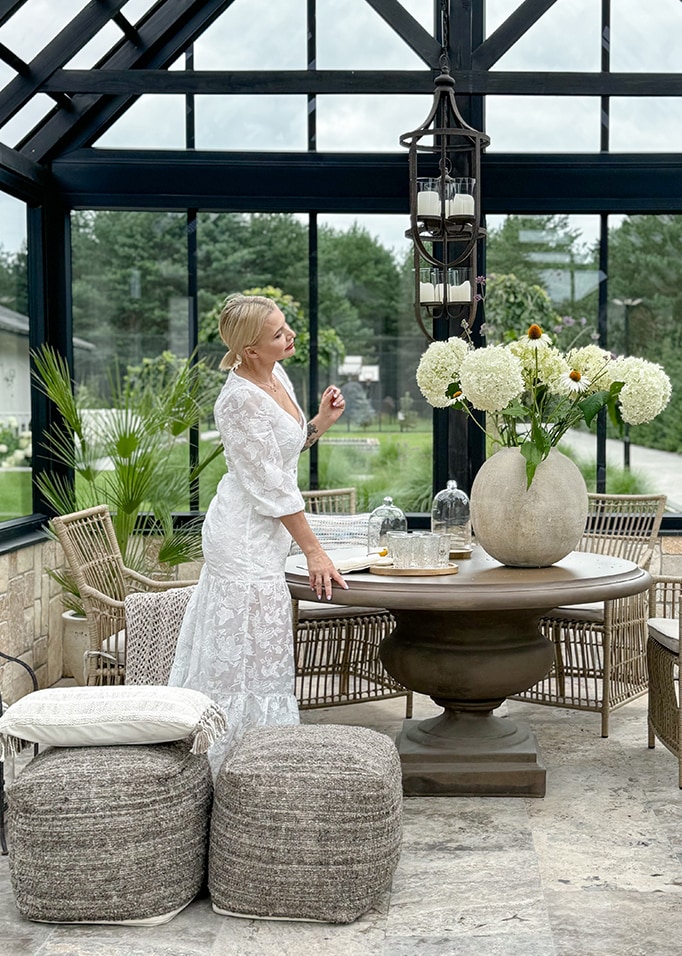 Gemütlicher Wintergarten mit rundem Steintisch, Korbstühlen und weisser Blumendekoration