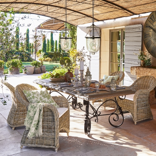 Gartenmöbel-Set aus Rattan und Metall in Naturtönen auf der Terrasse mit Dekorationen und Lampen