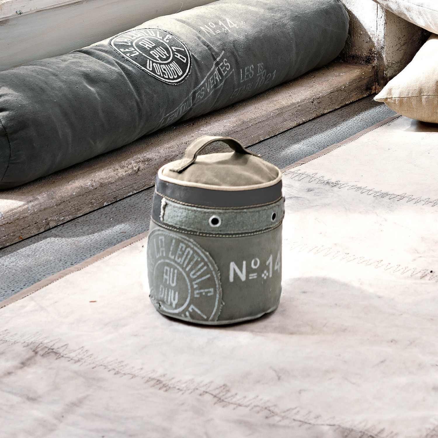 Türstopper au Puy Grauer Stoffbehälter mit Griff und Vintage-Aufdruck auf hellem Teppich im Loft-Stil