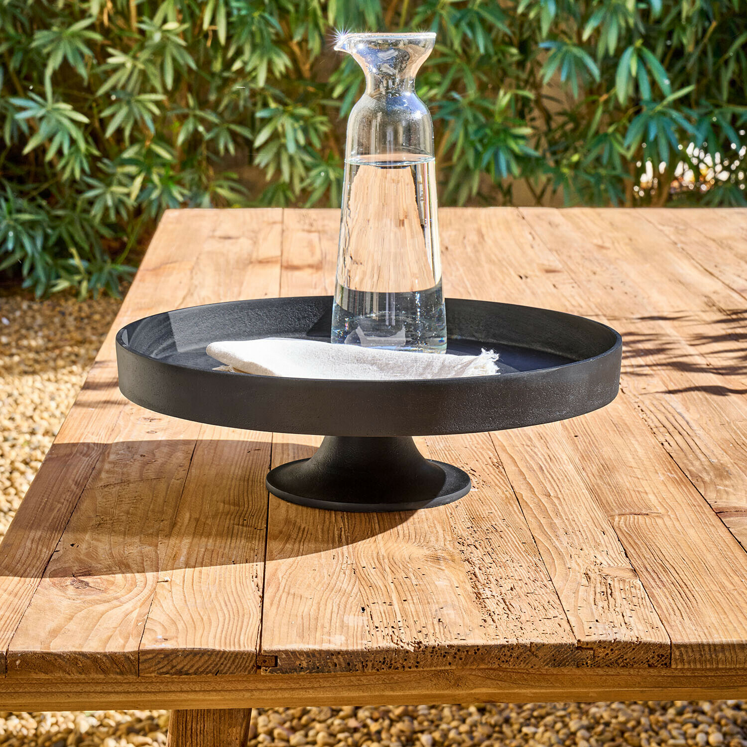 Etagere Varelle Schwarze Metall-Etagere auf Fuss mit klarem Glas-Krug und weisser Serviette auf Holztisch
