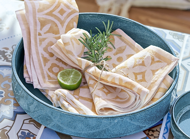 Blaue Keramikschale mit beige-weissen Leinenservietten und Limettenscheibe im mediterranen Stil