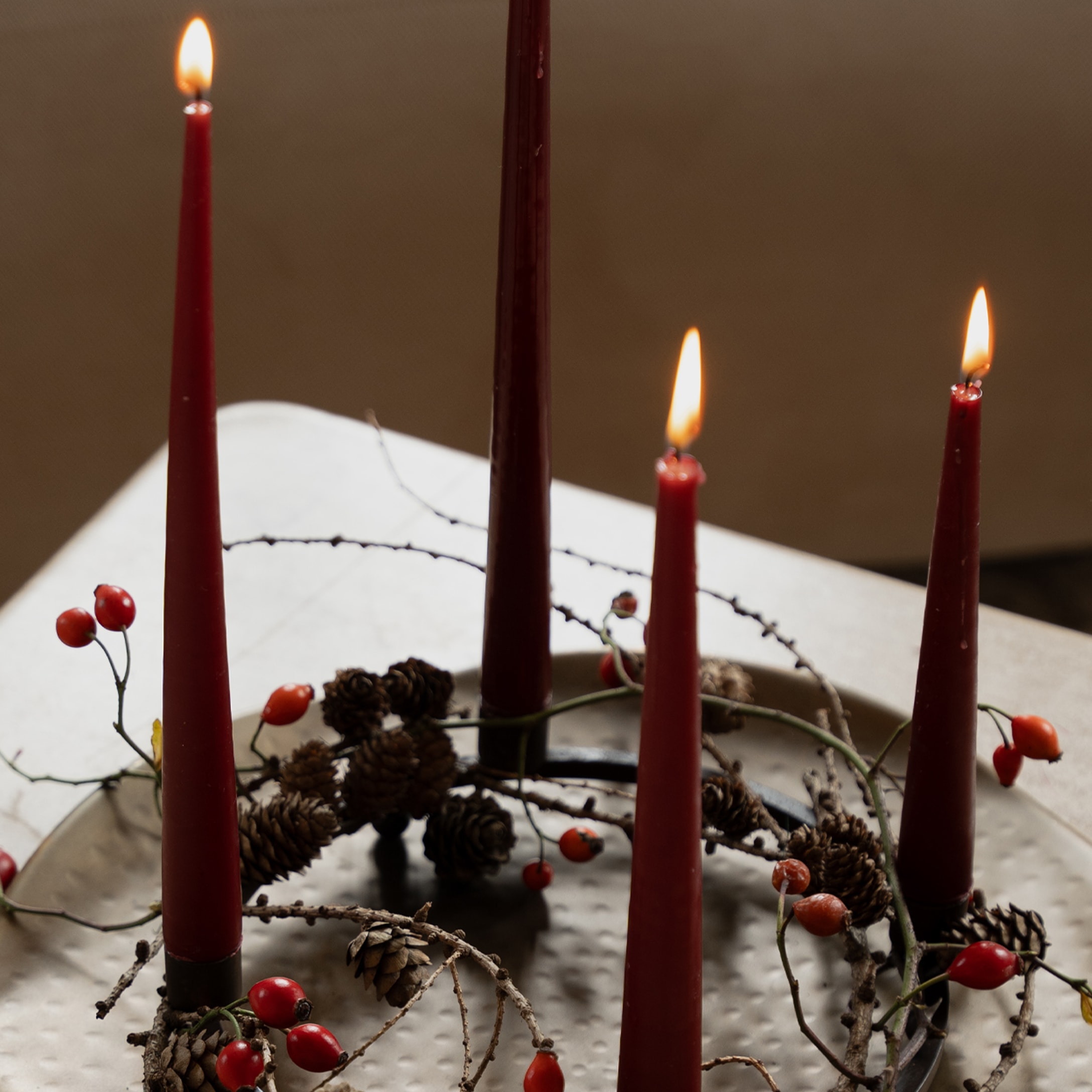 Adventskranz mit roten Kerzen, Tannenzapfen und roten Beeren auf Metallring