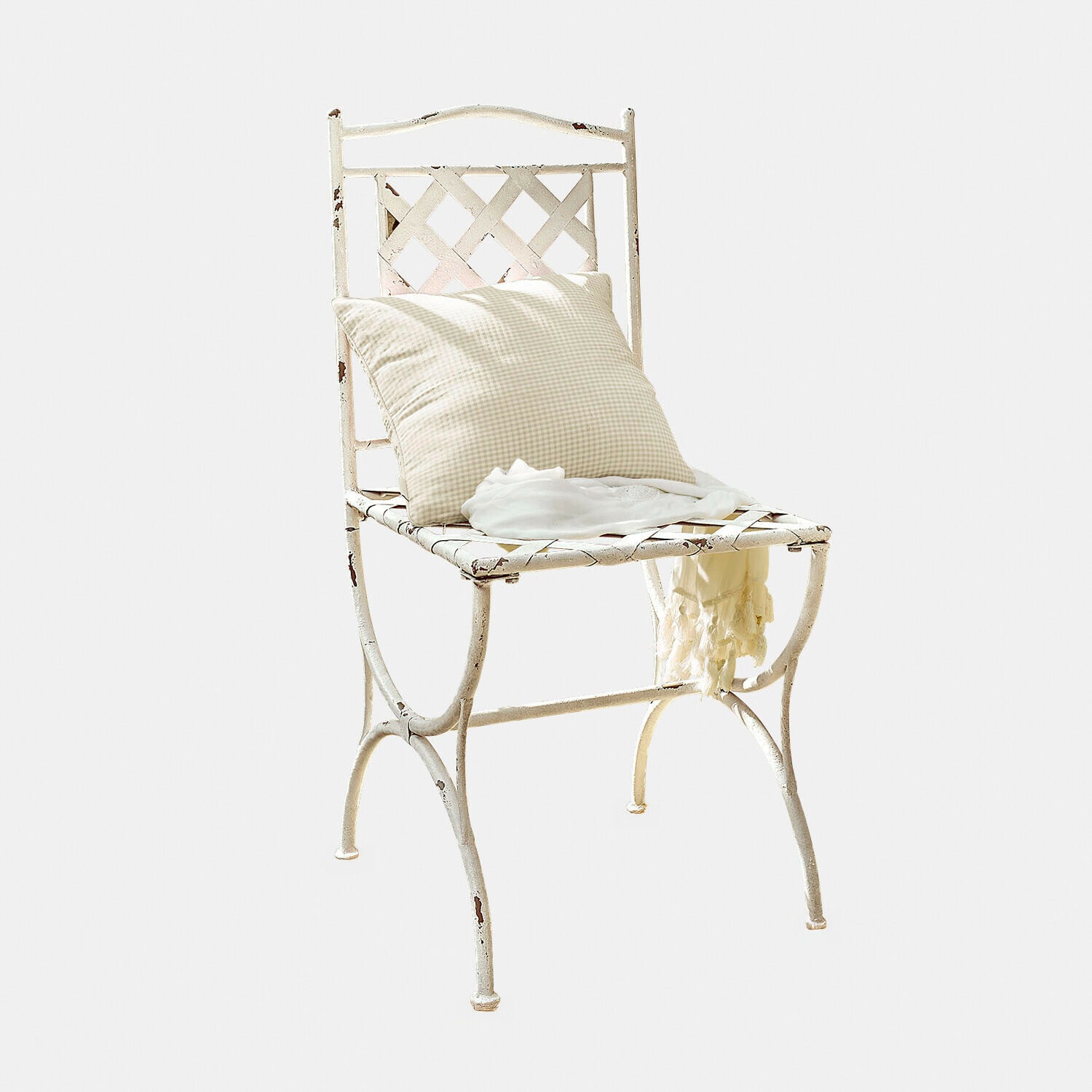Weisser Vintage Metallstuhl mit kariertem Kissen und hellem Schal darauf