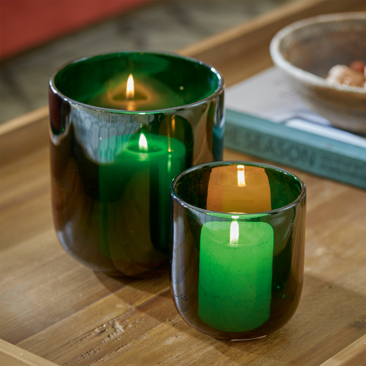 Windlicht 2er Set Theodor Zwei grüne Glaswindlichter mit brennenden Kerzen auf Holztisch, stimmungsvolle Wohnraumdekoration
