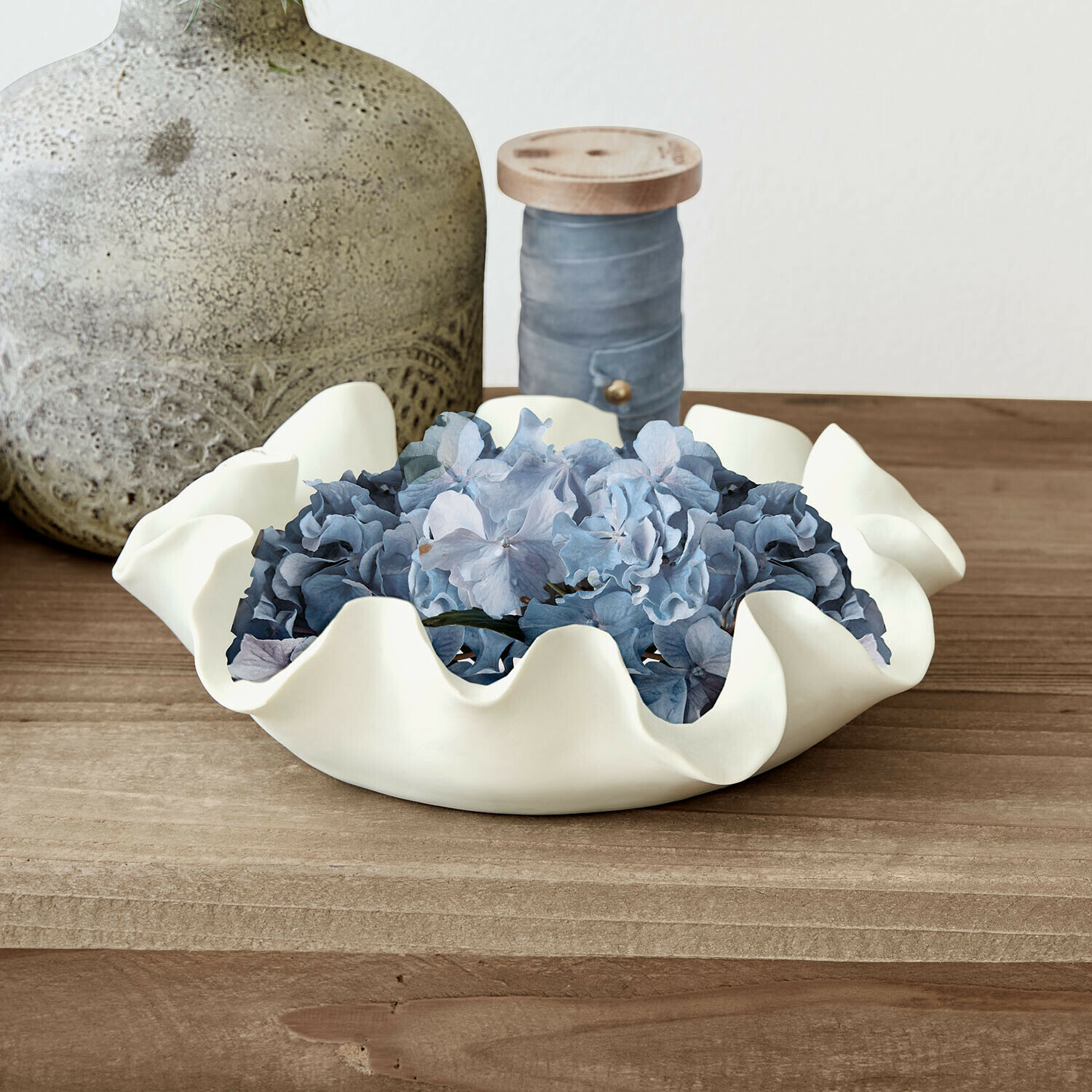 Schale Lunettas Weisse Keramikschale mit welligem Rand und blauen Blumen auf Holztisch