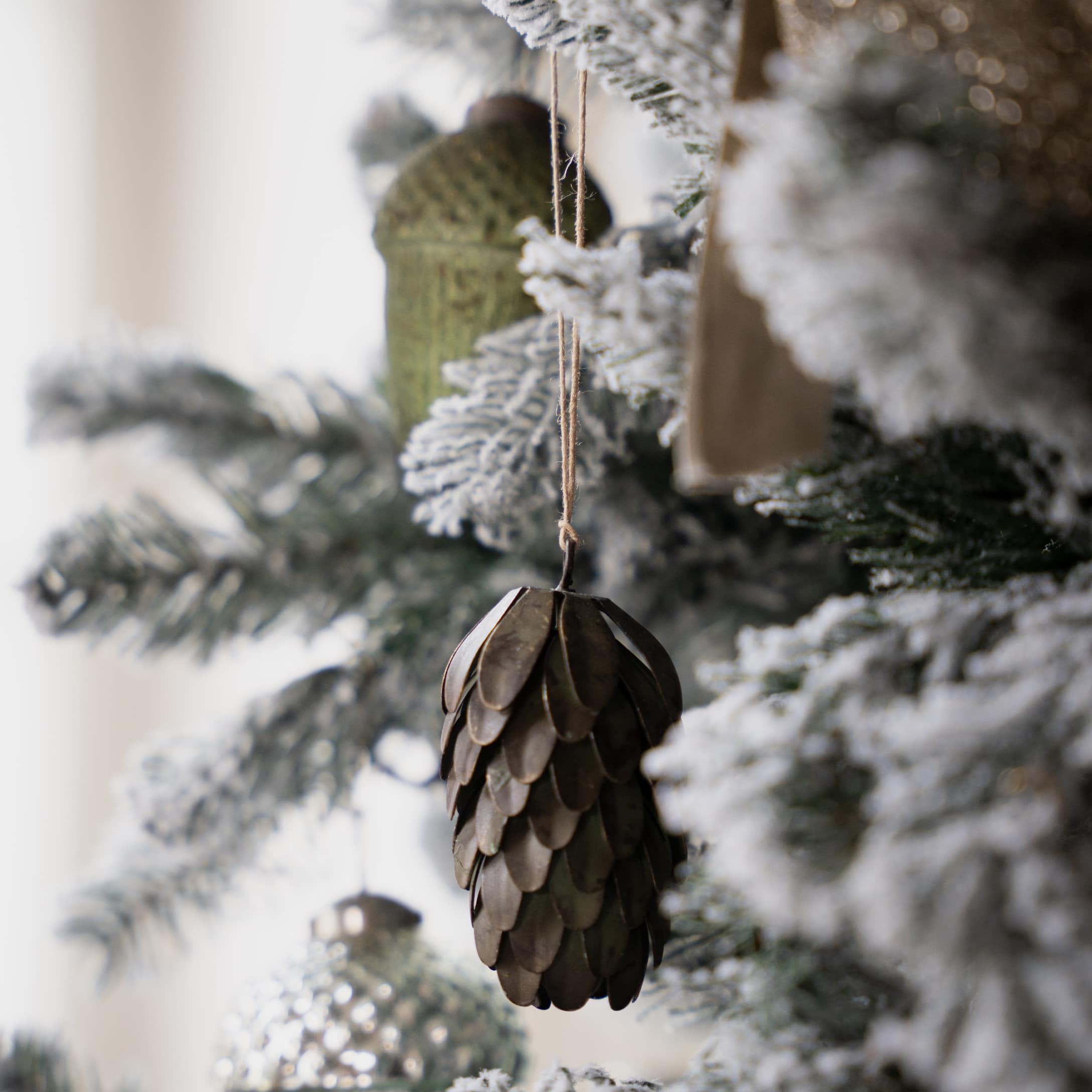 Braune Metall-Weihnachtsschmuckzapfen an schneebedecktem Weihnachtsbaum