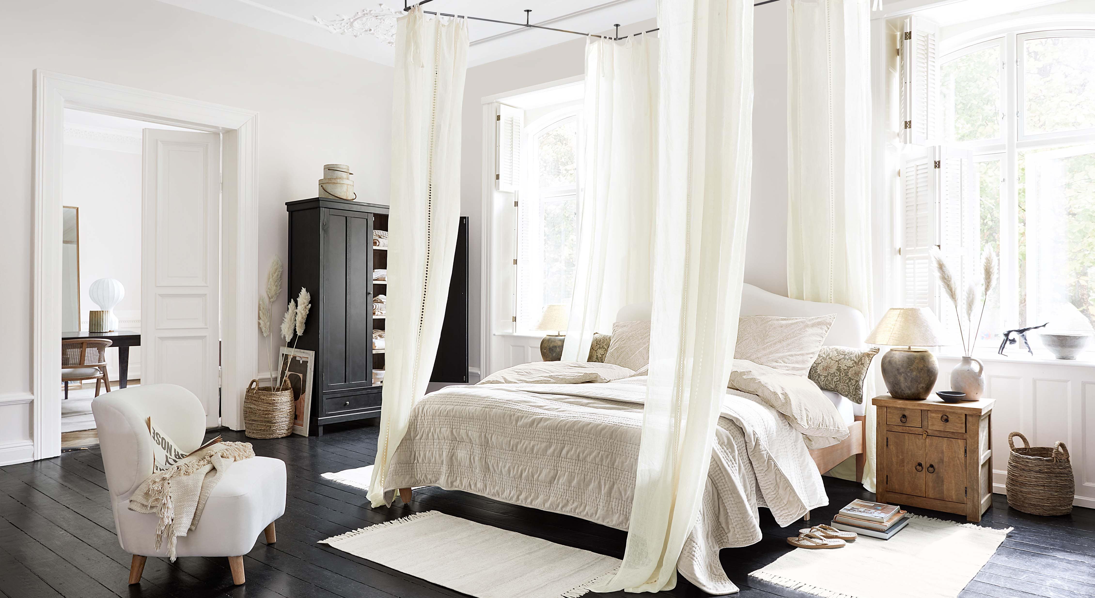 Gemütliches Schlafzimmer mit Himmelbett, hellbeiger Bettwäsche und skandinavischen Holzmöbeln