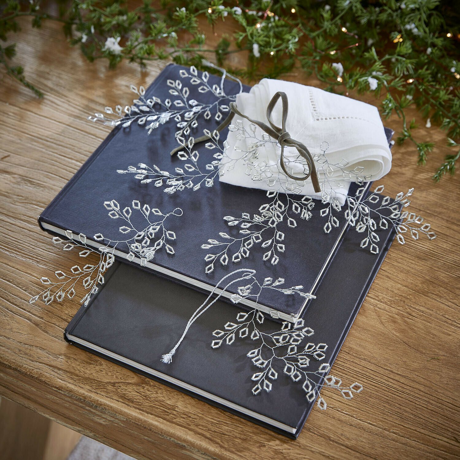 Ornament 6er Set Alruna Zwei dunkelblaue und schwarze Alben auf Holztisch mit weisser Leinenserviette und Kristalldekoration