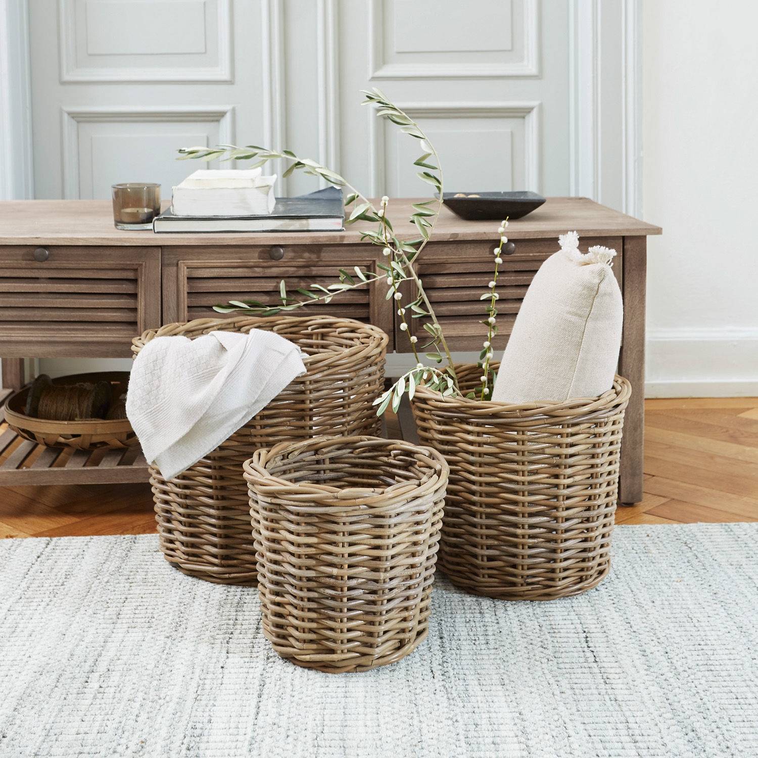 Korb 3er Set Avar Drei natürliche Körbe aus Rattan zum Aufbewahren im Wohnbereich auf hellem Teppich.