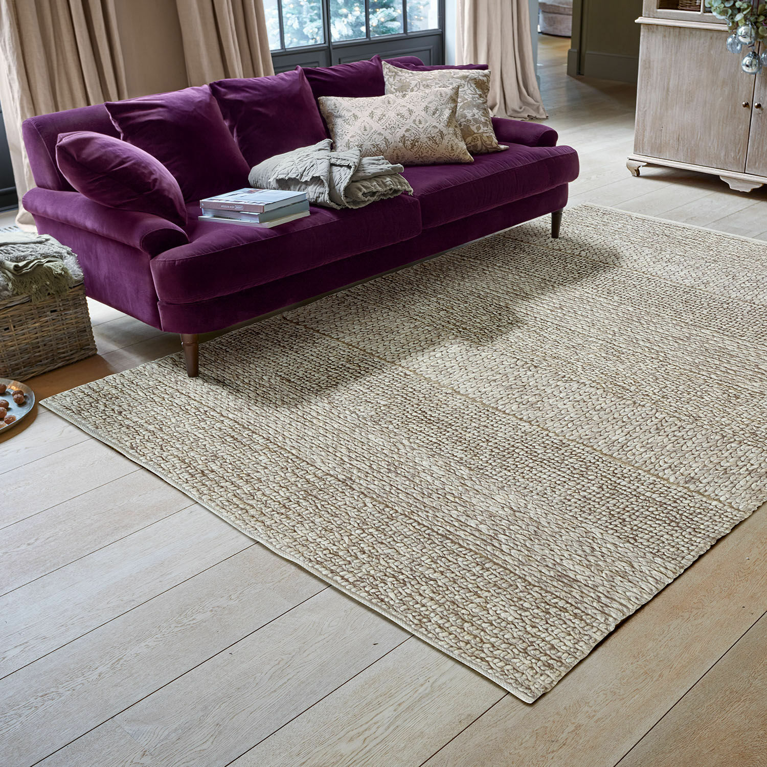 Teppich Welezas Beiger Teppich aus Naturmaterial mit geflochtener Struktur im modernen Wohnzimmer mit violettem Sofa