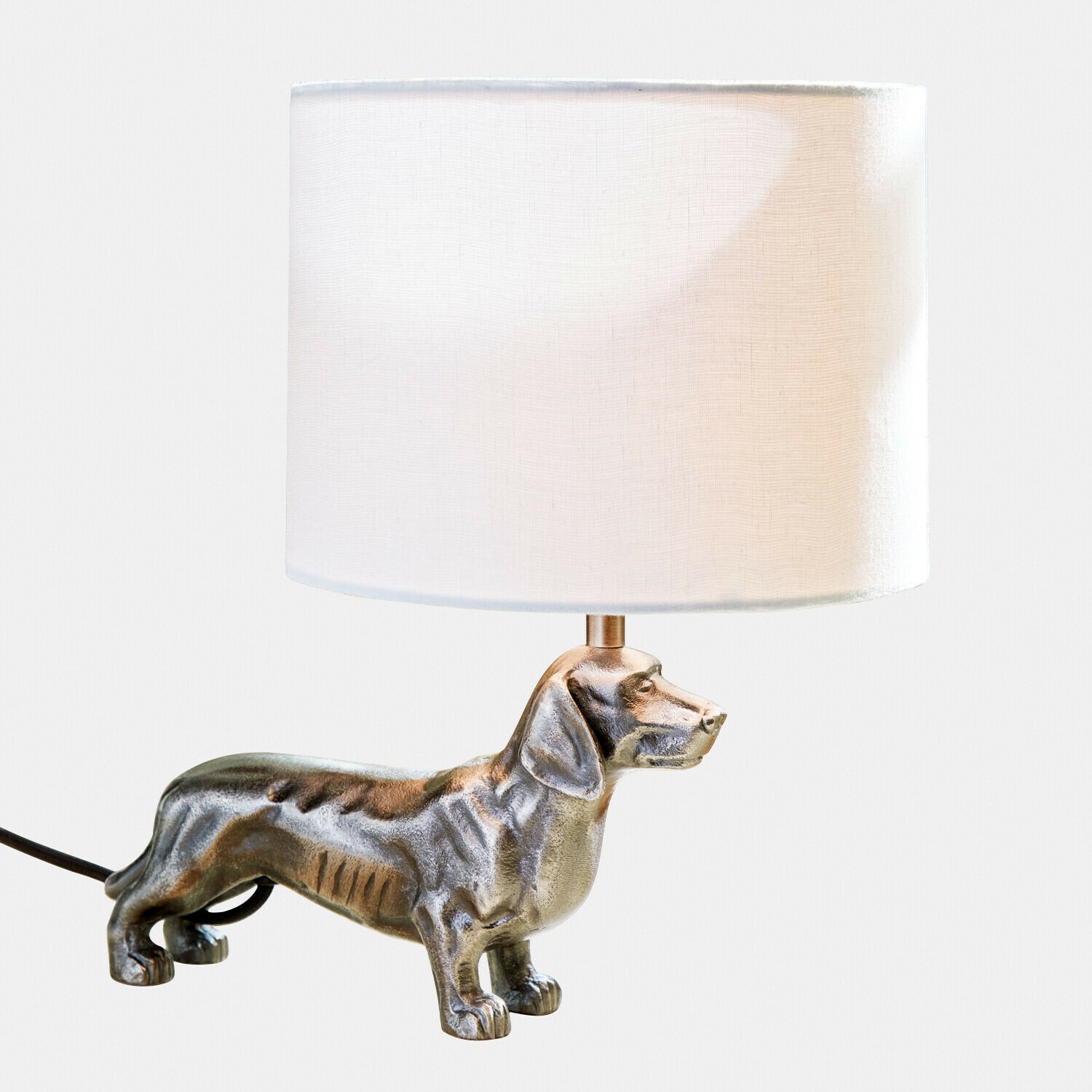 Tischlampe mit weissem Lampenschirm und silberner Dackelfigur als Lampenfuss