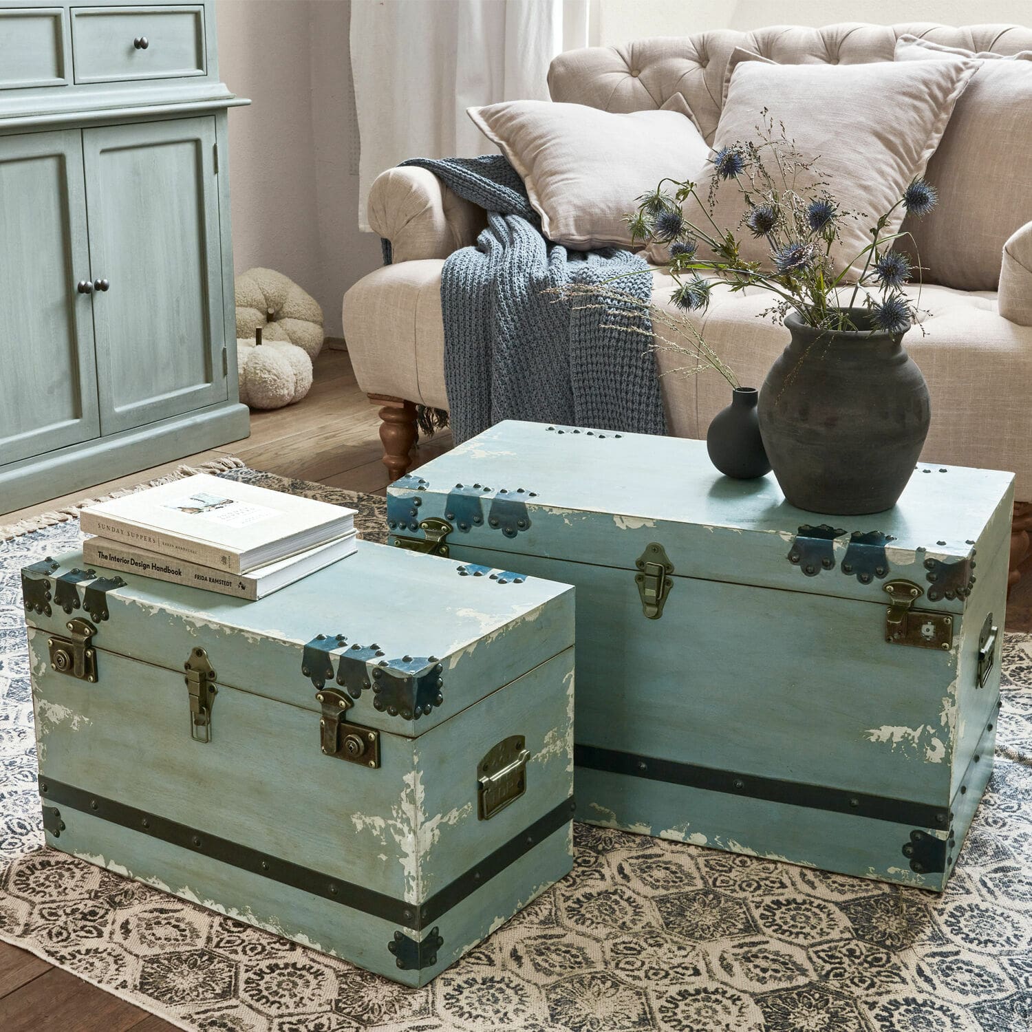 Truhe 2er Set Gorman Zwei blaue Holzkoffer mit Metallbeschlägen auf dem Teppich im Wohnzimmer mit beigem Sofa
