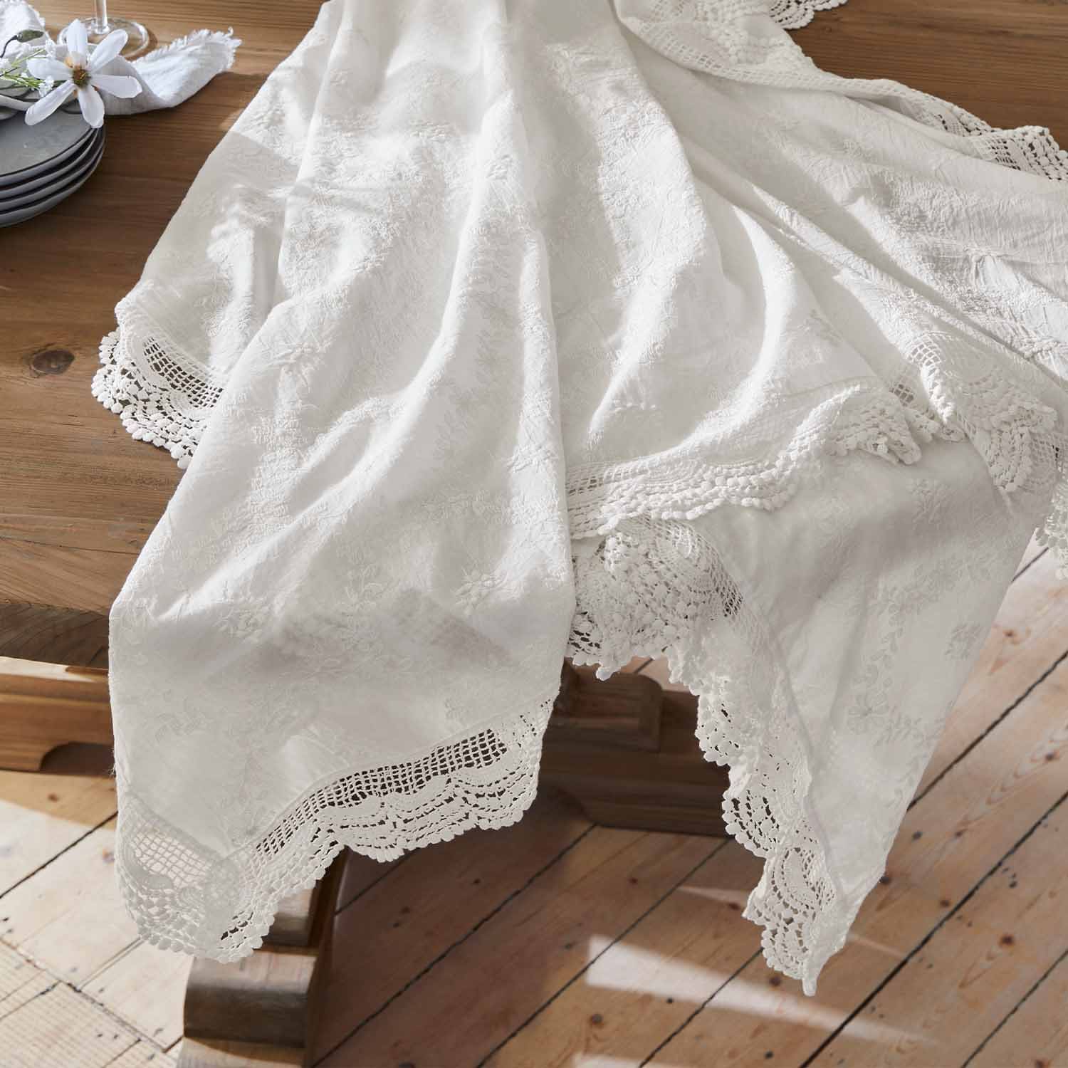 Weisser bestickter Tischläufer mit Spitzenrand auf Holztisch, elegante Tischdekoration