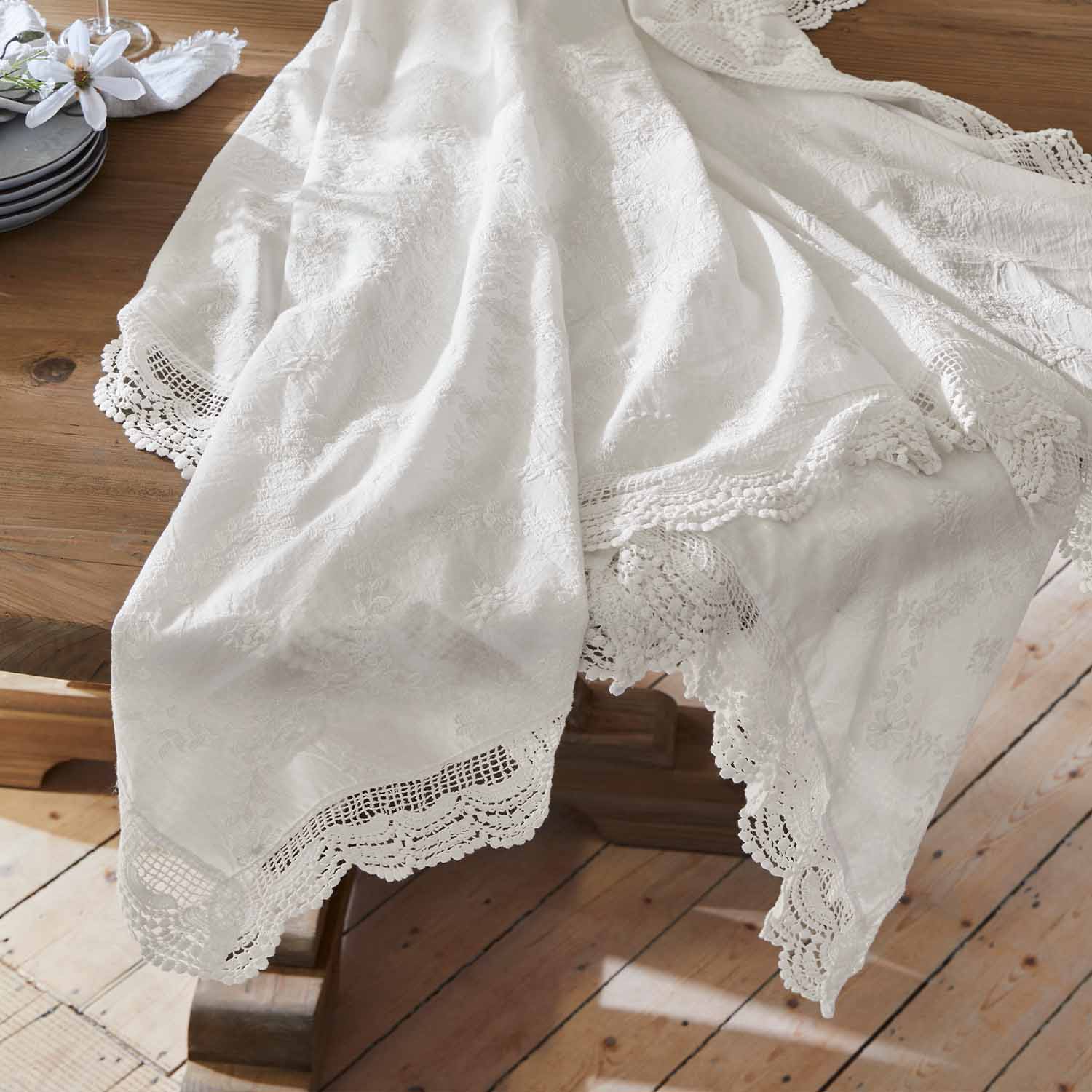 Weisser bestickter Tischläufer mit Spitzenrand auf Holztisch, elegante Tischdekoration