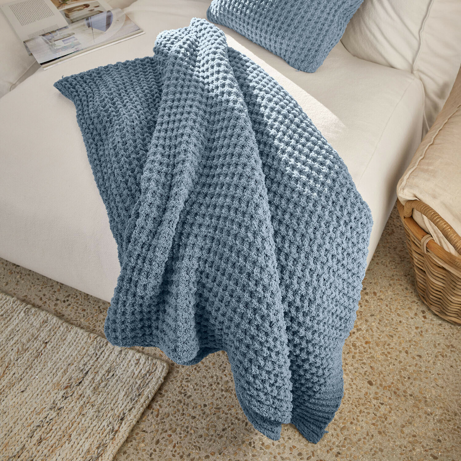 Weiche blaue Waffeldecke auf hellem Sofa, dekorativer und gemütlicher Wohnzimmerschal