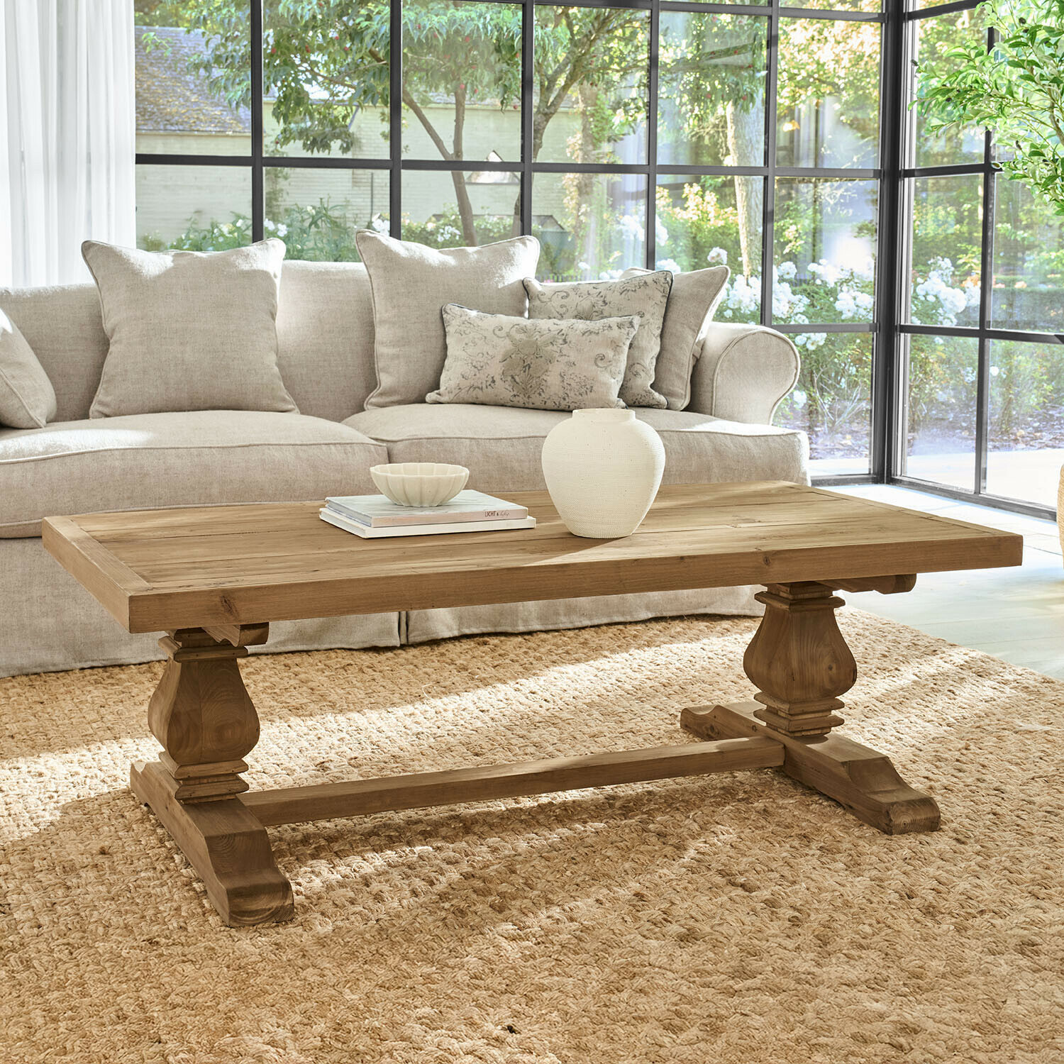 Couchtisch Ellestone Holz-Couchtisch in Naturfarbe mit verzierten Beinen im hellen Wohnzimmer mit beigem Sofa
