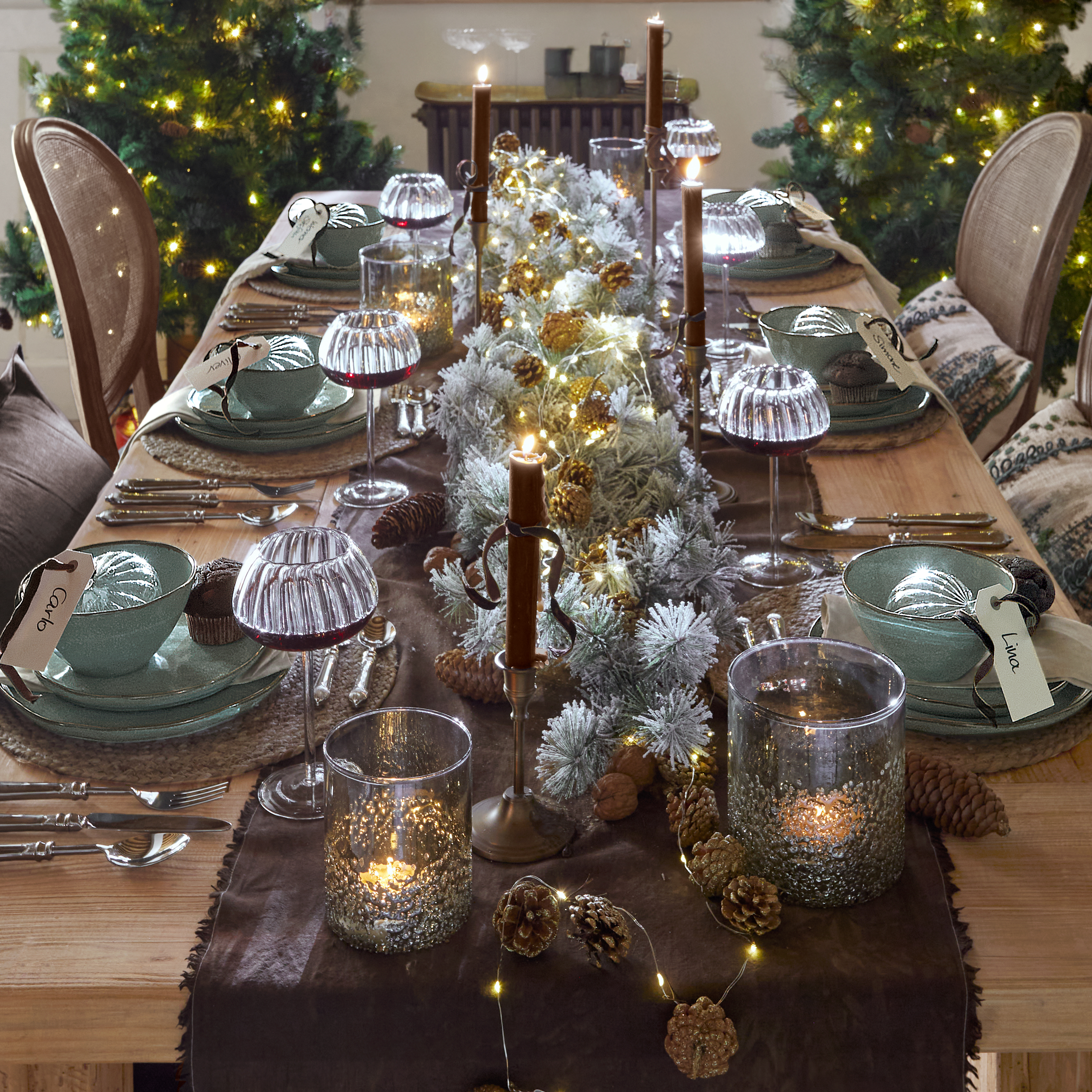 Weihnachtlich gedeckter Holztisch mit grüner Keramik, Kerzen und LED-Lichterkette als festliche Dekoration