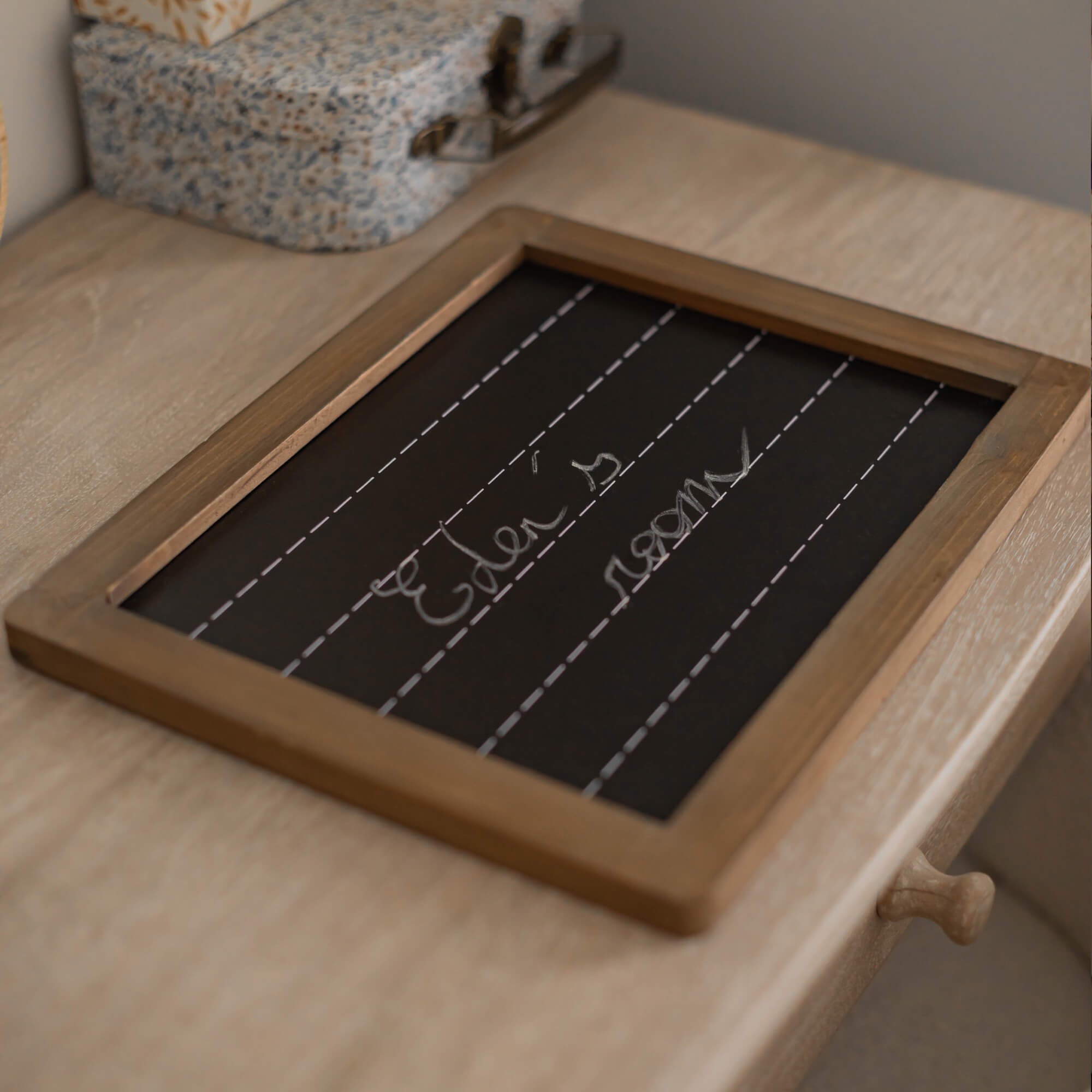 Kreidetafel mit Holzrahmen auf hellem Holztisch, dekoratives Wohnaccessoire