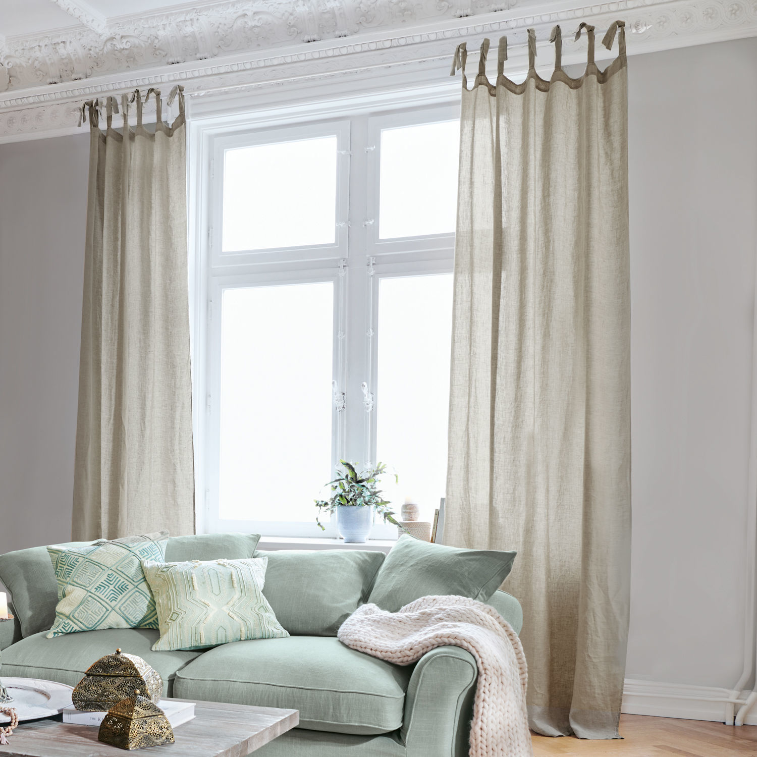 Gardine Monthelie Beige Leinenvorhänge am Fenster im hellen Wohnzimmer mit grünem Sofa und dekorativen Kissen
