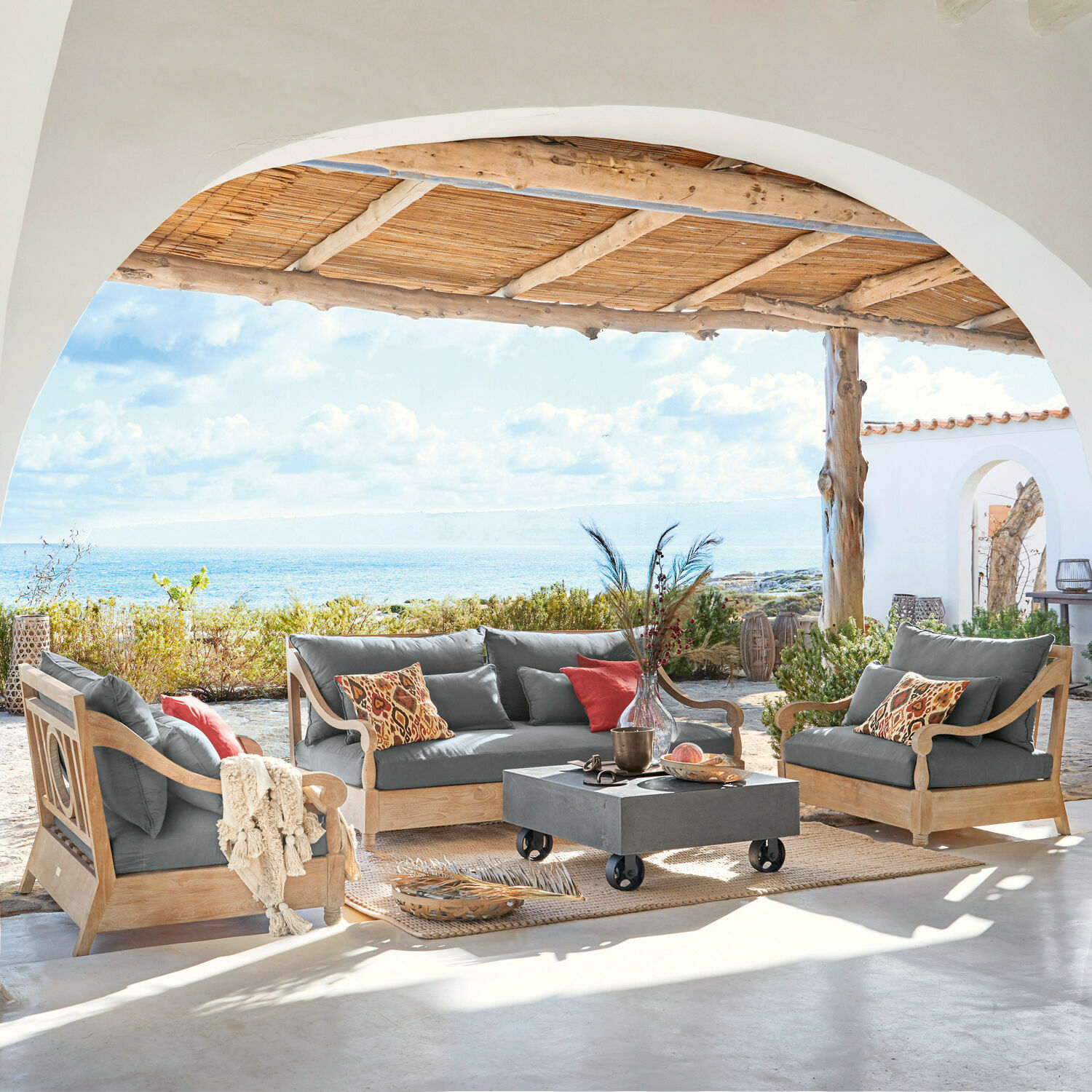 Sitzgruppe Montcassin Gartenmöbel-Set aus Holz mit grauen Polstern auf der Terrasse mit Meerblick