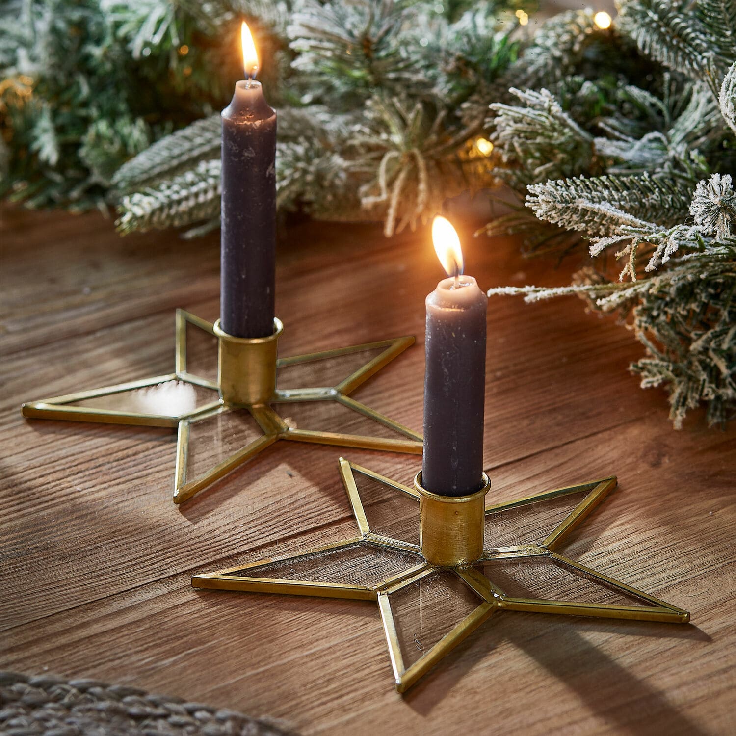Kerzenständer 2er Set Zaydan Zwei sternförmige Kerzenhalter aus Glas und goldenem Metall mit violetten Kerzen auf dem Holztisch