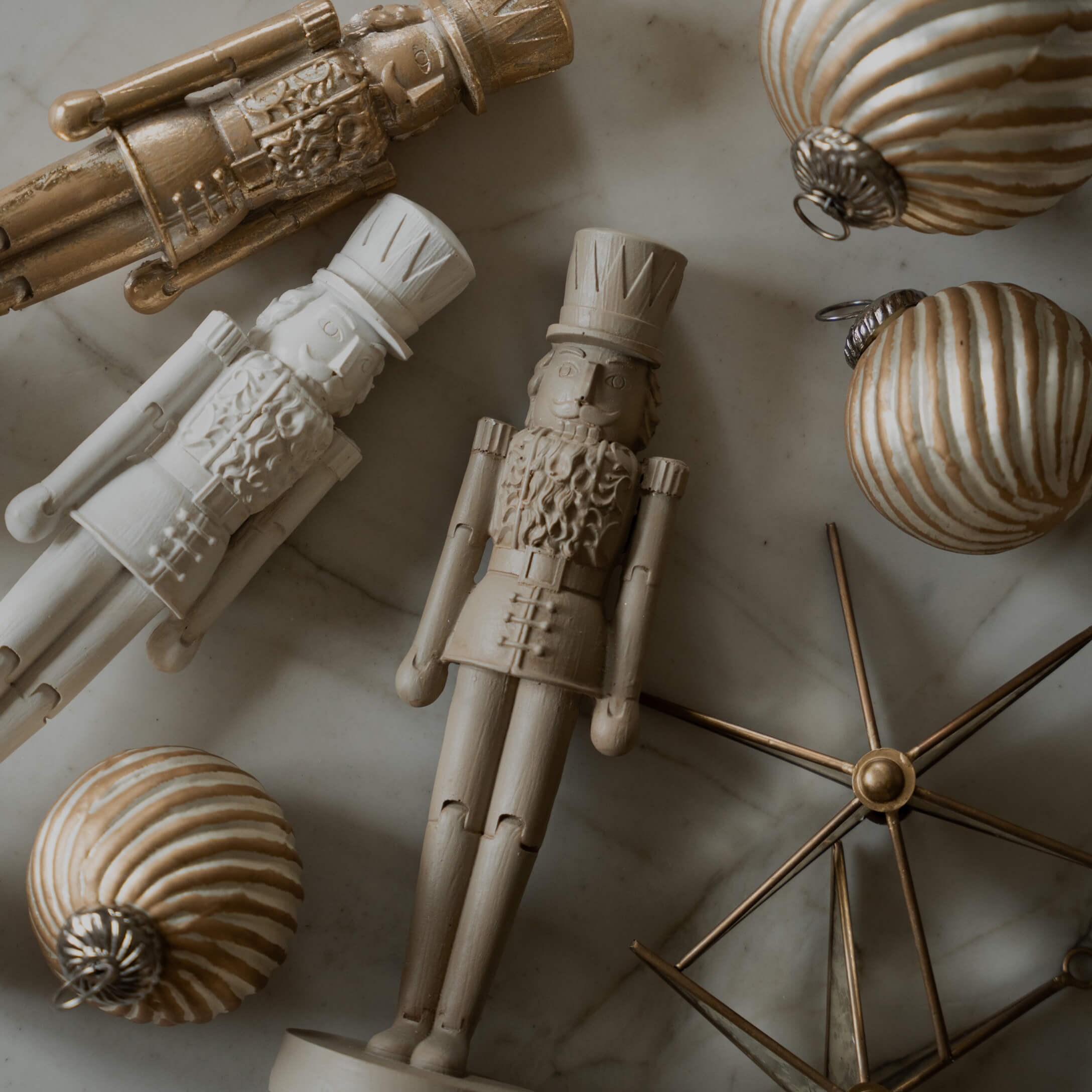 Holz-Nussknackerfiguren und goldene Weihnachtskugeln auf Marmorhintergrund, festliche Dekoration