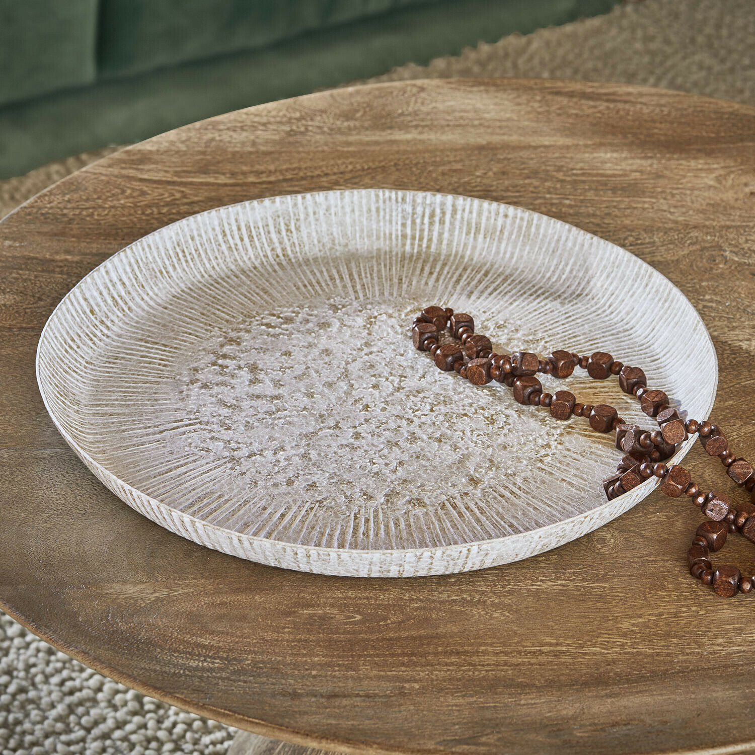 Tablett Gravière Rundes dekoratives Tablett aus weißem Holz mit Struktur auf Holztisch mit brauner Perlenkette