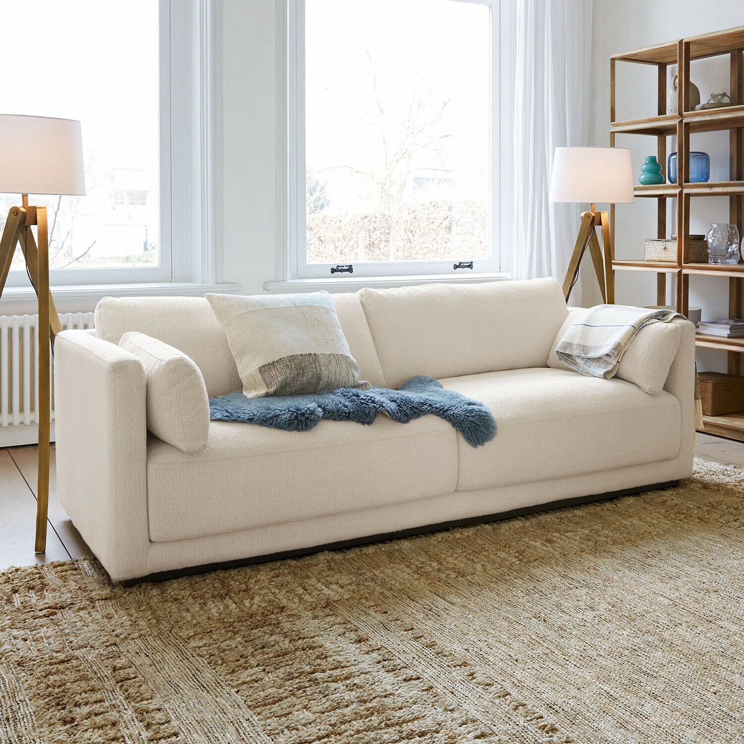 Moderne cremefarbene Sofa mit weichem Stoff und dekorativen Kissen im hellen Wohnzimmer
