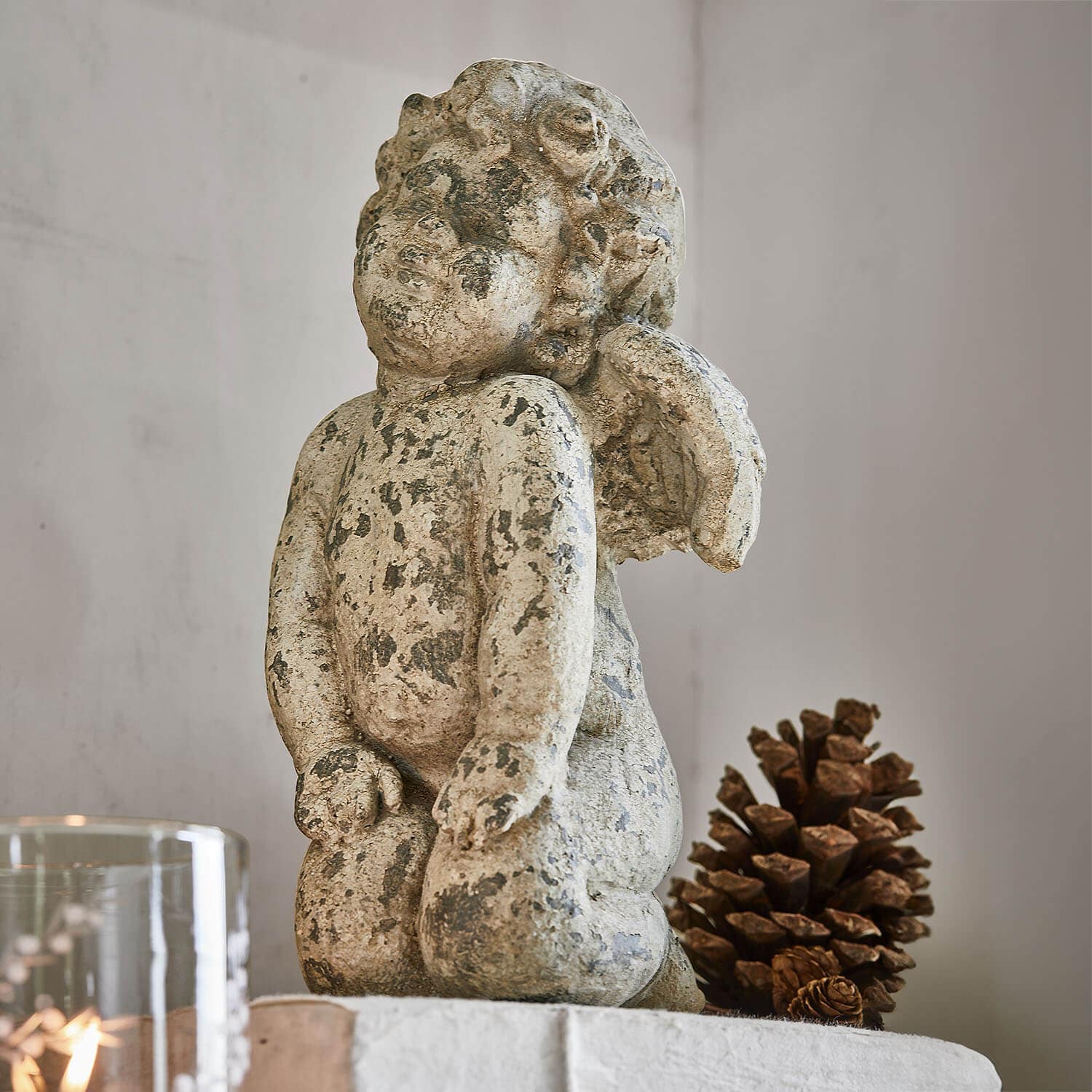 Engelsfigur aus gealtertem Stein in Beige, Wohnaccessoire mit natürlicher Kiefernzapfen-Dekoration