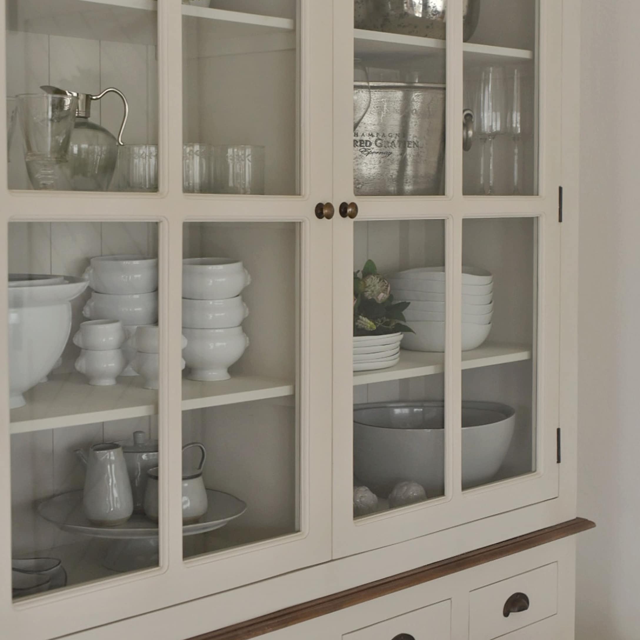Weisser Holzschrank mit Glastüren, weissem Porzellan und Gläsern im Innern