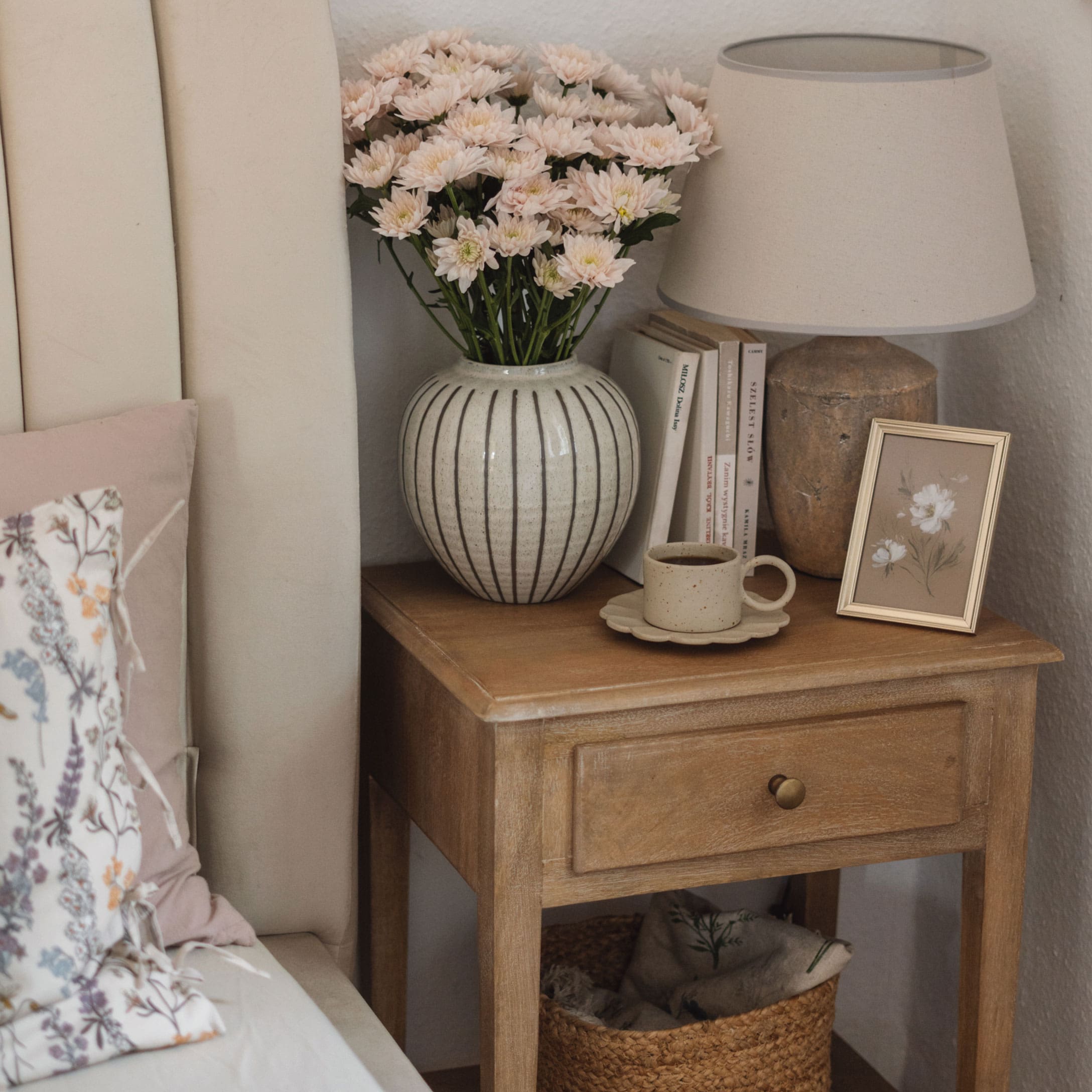 Holz-Nachttisch mit gestreifter Keramikvase, Blumen, Lampe und Kaffeetasse in Beige