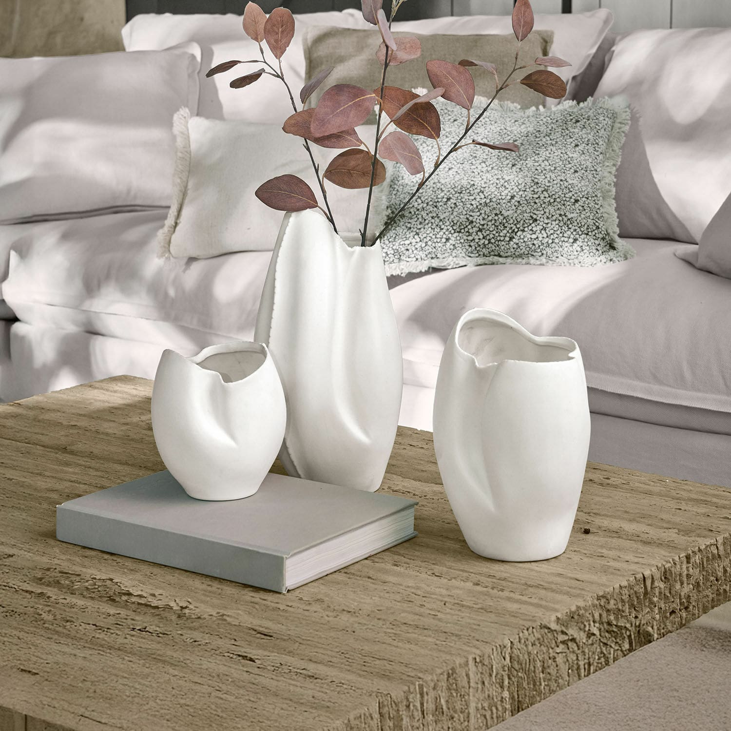 Vase 3er Set Kazimad Drei weiße Keramikvasen mit unregelmässiger Form auf einem Holztisch im Wohnzimmer