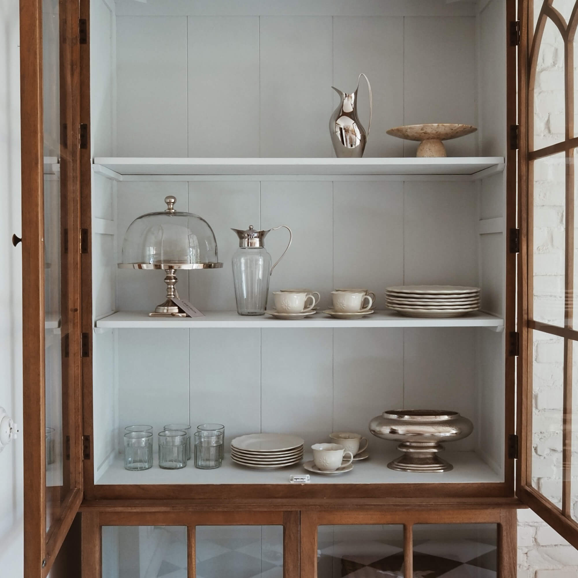 Holzvitrine mit weissen Regalen, Porzellanservice und Gläsern für den Haushalt
