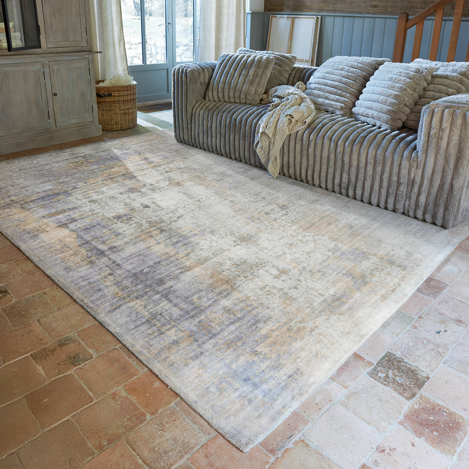 Teppich Qalheera Dekorativer Teppich in Beige- und Grautönen vor grauem Sofa im Wohnzimmer