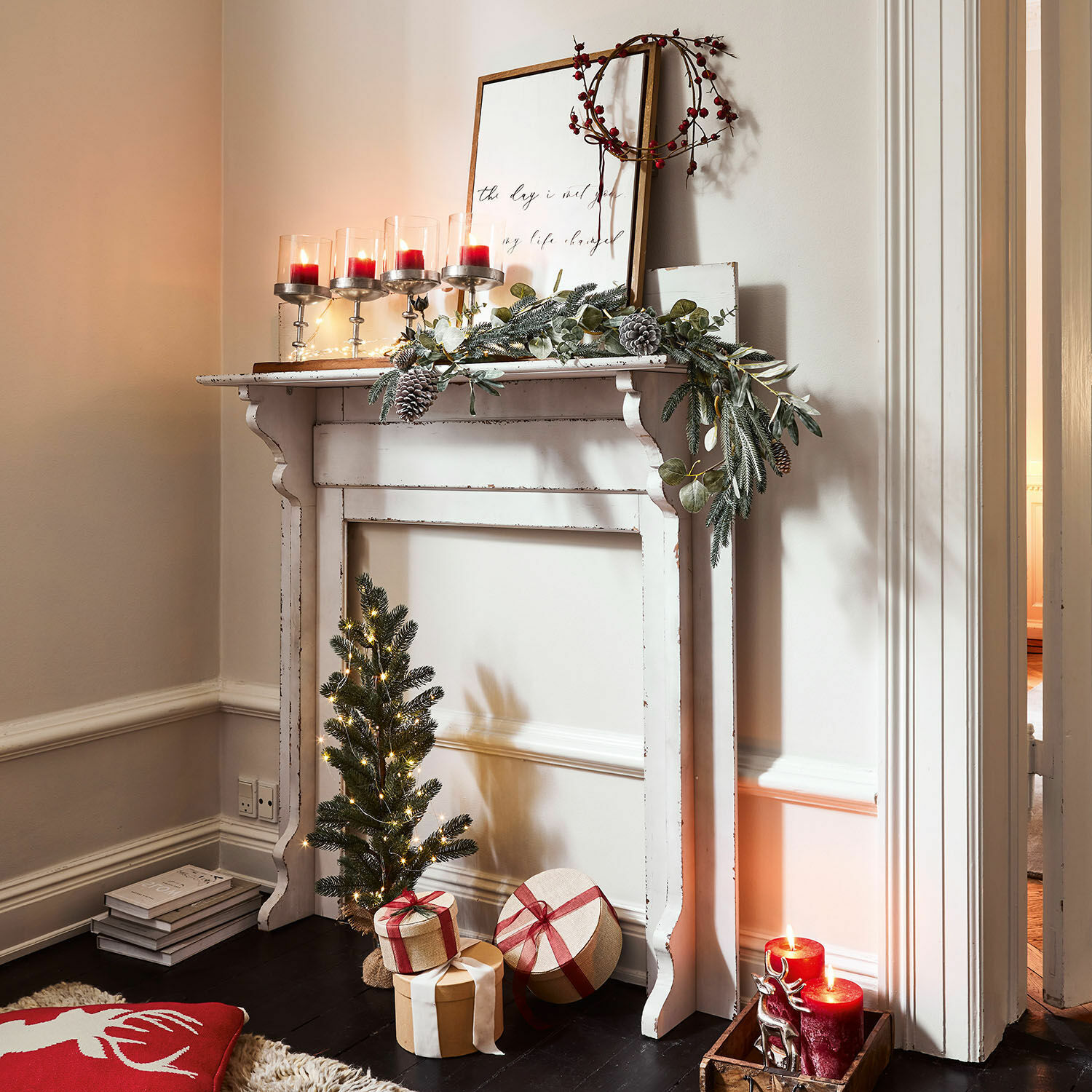 Kaminkonsole Cessieu Weisser dekorativer Holz-Kamin mit grünem Kranz, roten Kerzen und Weihnachtsgeschenken