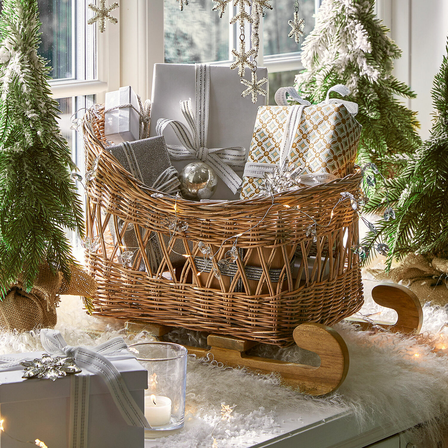 Deko-Schlitten Quileta Wikinger-Schlitten aus Korbgeflecht mit Holzschlittenkufen, gefüllt mit silberweissen Geschenkpaketen im Weihnachtsdekor