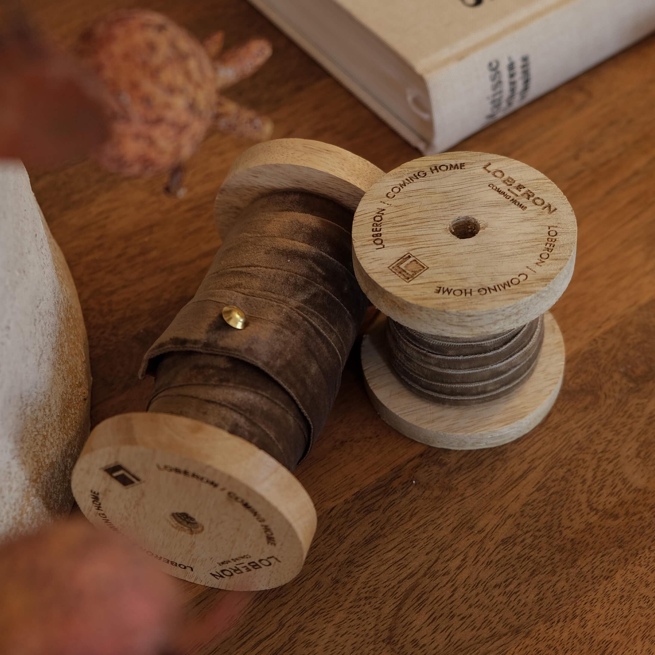 Holzspulen mit braunem Samtband auf Holztisch, dekoratives Wohnaccessoire